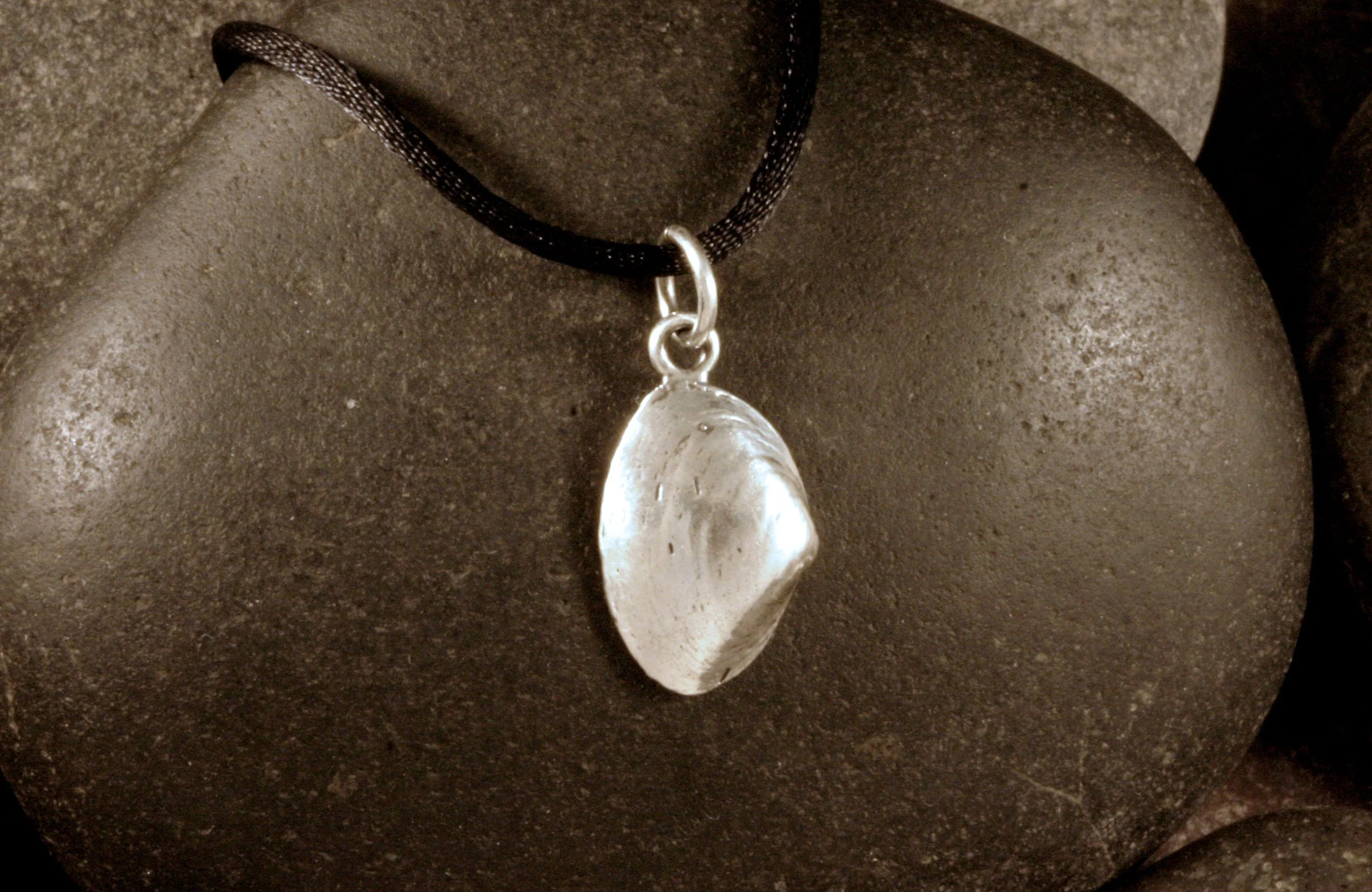 An oxidized sterling silver small surf clam shell charm.