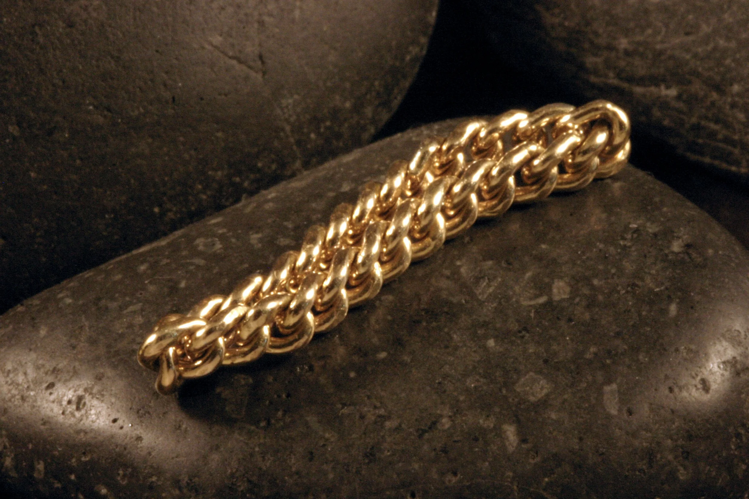 A 14K gold curb chain fidget ring shown folded together.