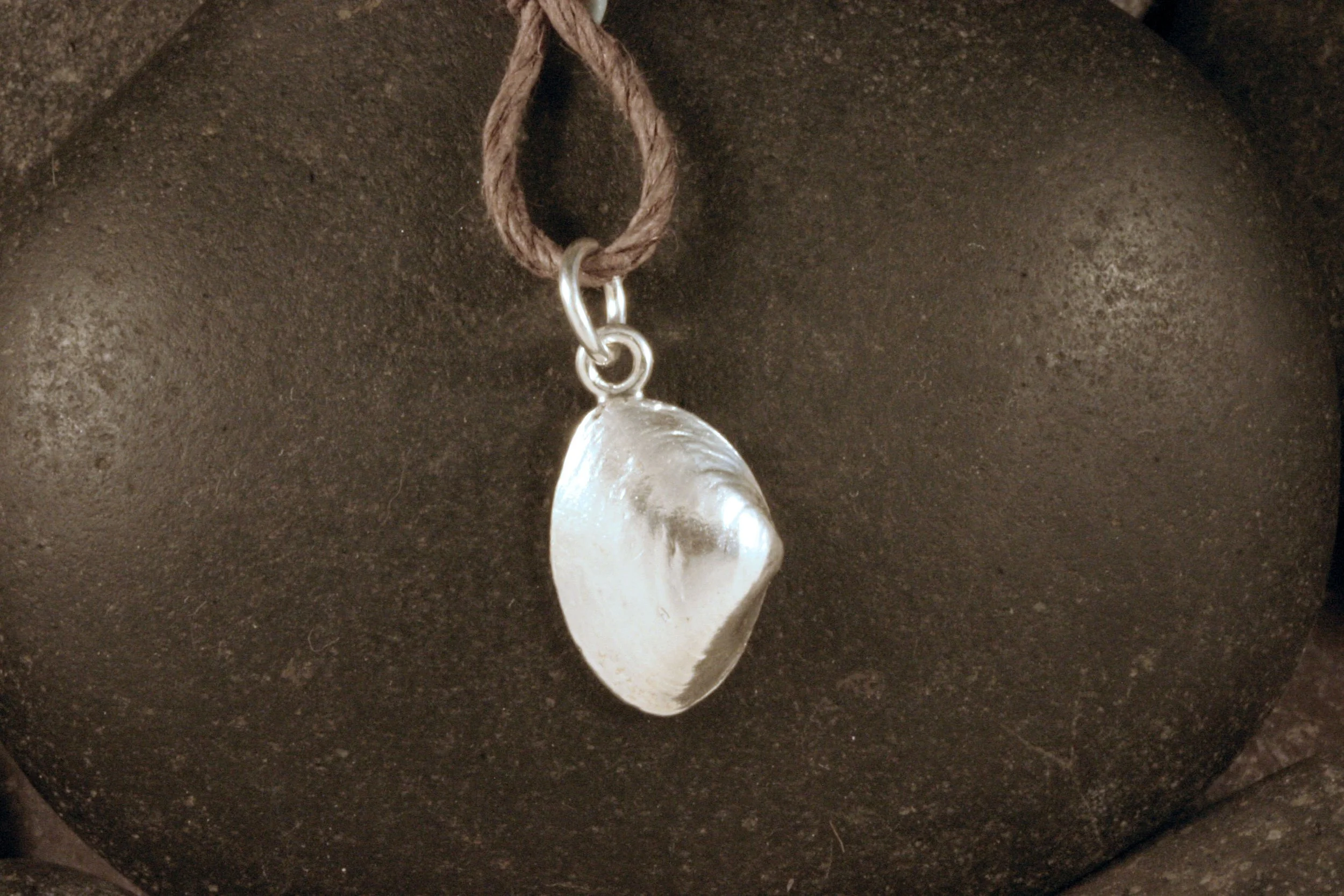 A shiny sterling silver small surf clam shell charm.