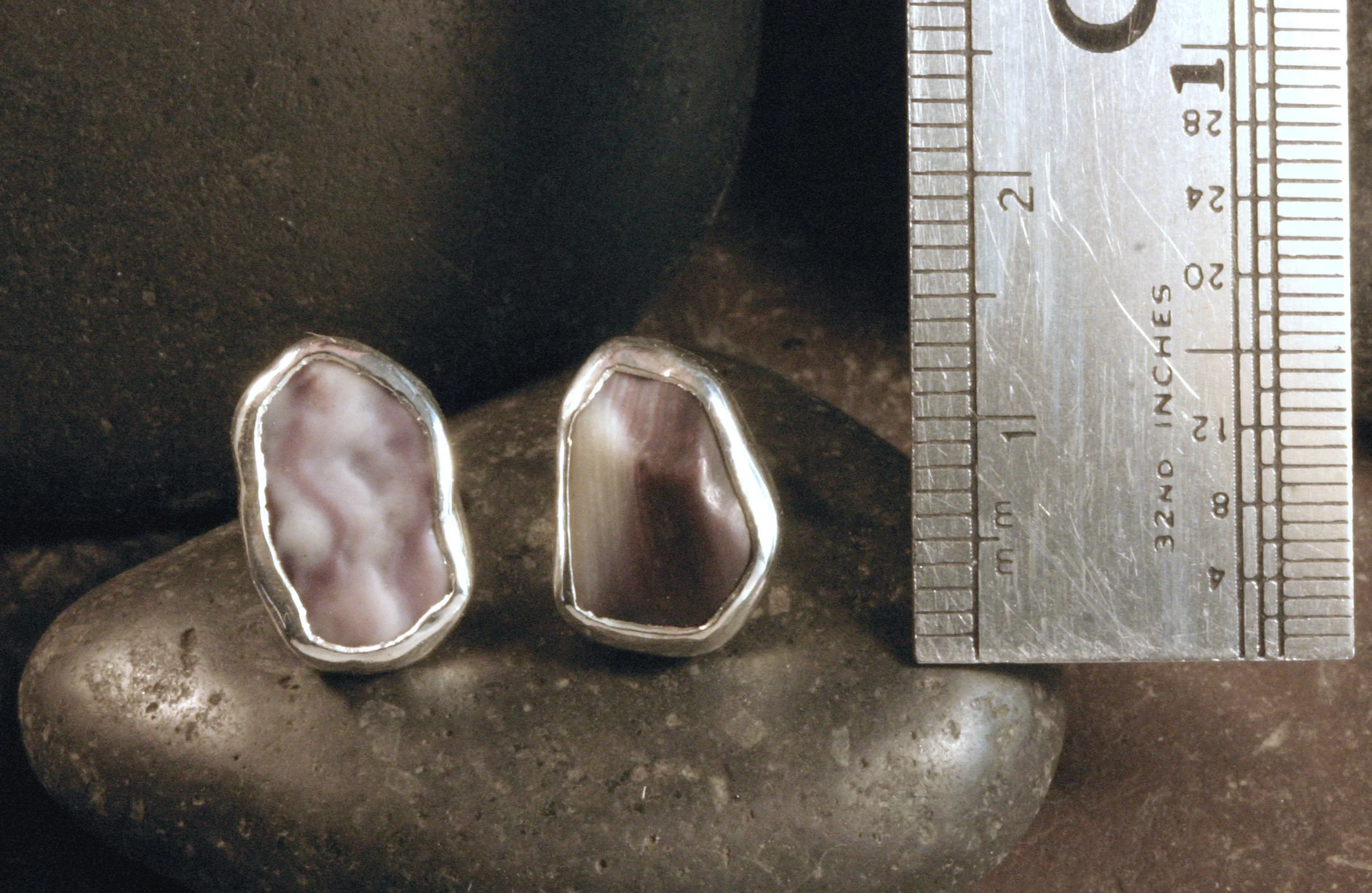 Small sterling silver freeform pentagon wampum studs next to a ruler.