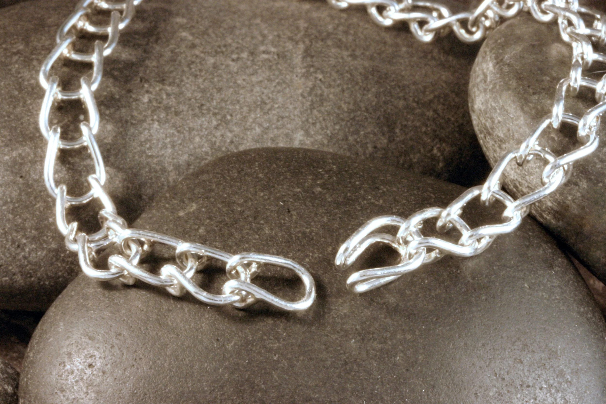 A sterling silver horseshoe shaped U link chain bracelet showing its hidden clasp open.