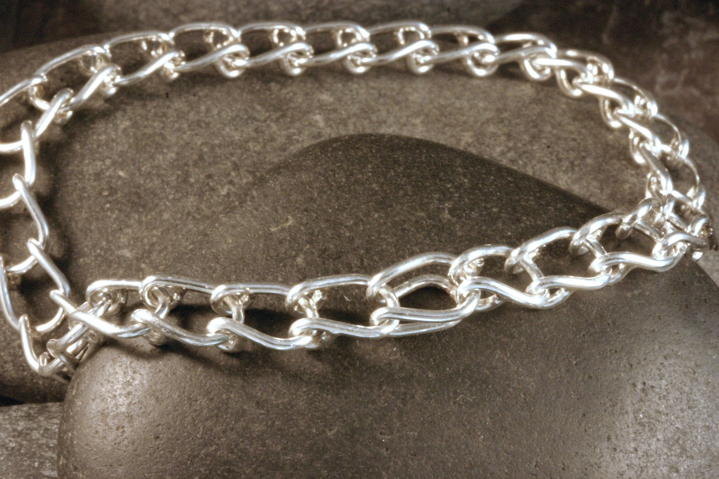 A sterling silver horseshoe shaped U link chain bracelet showing its hidden clasp closed.