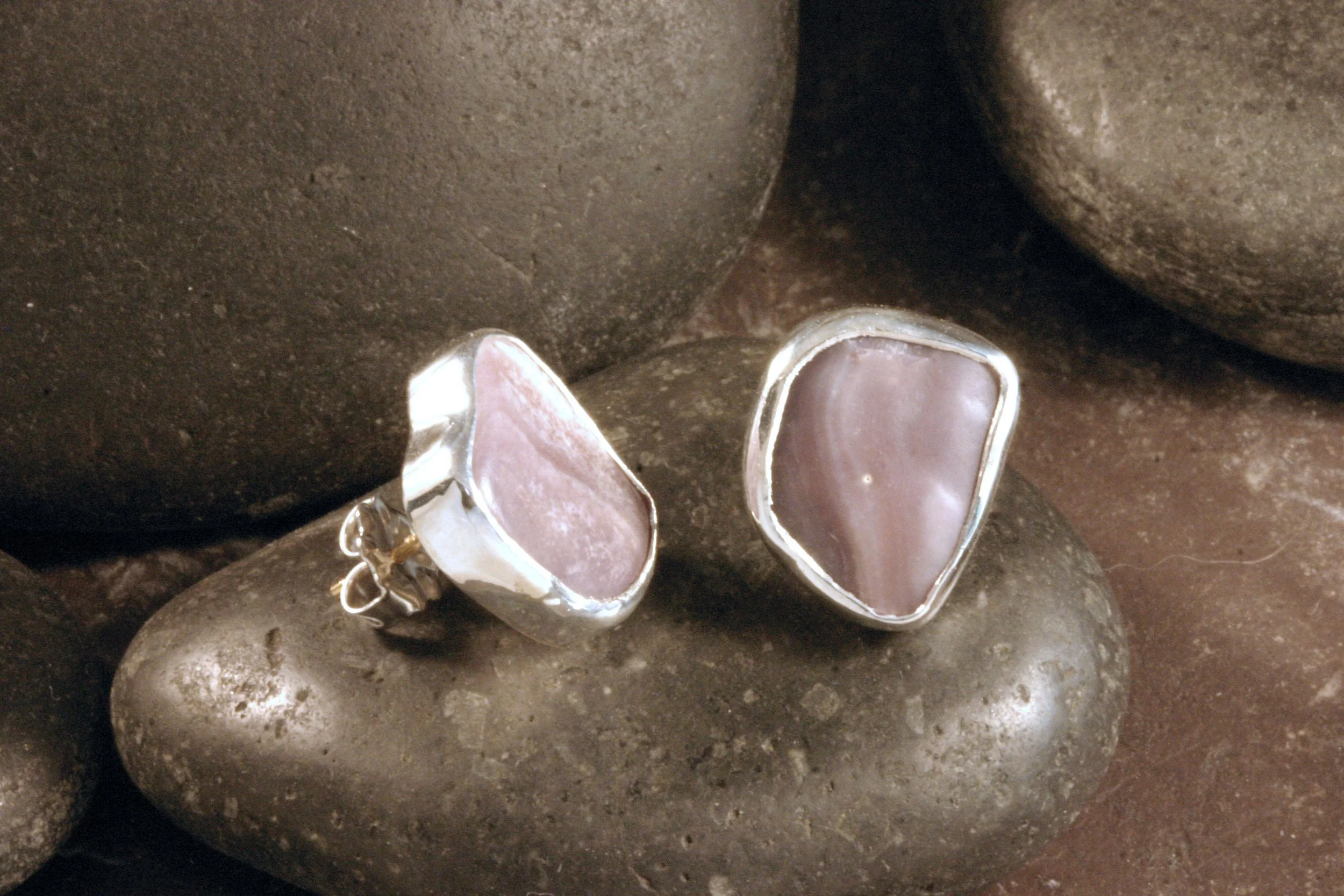 A side view of small sterling silver freeform wampum stud earrings.