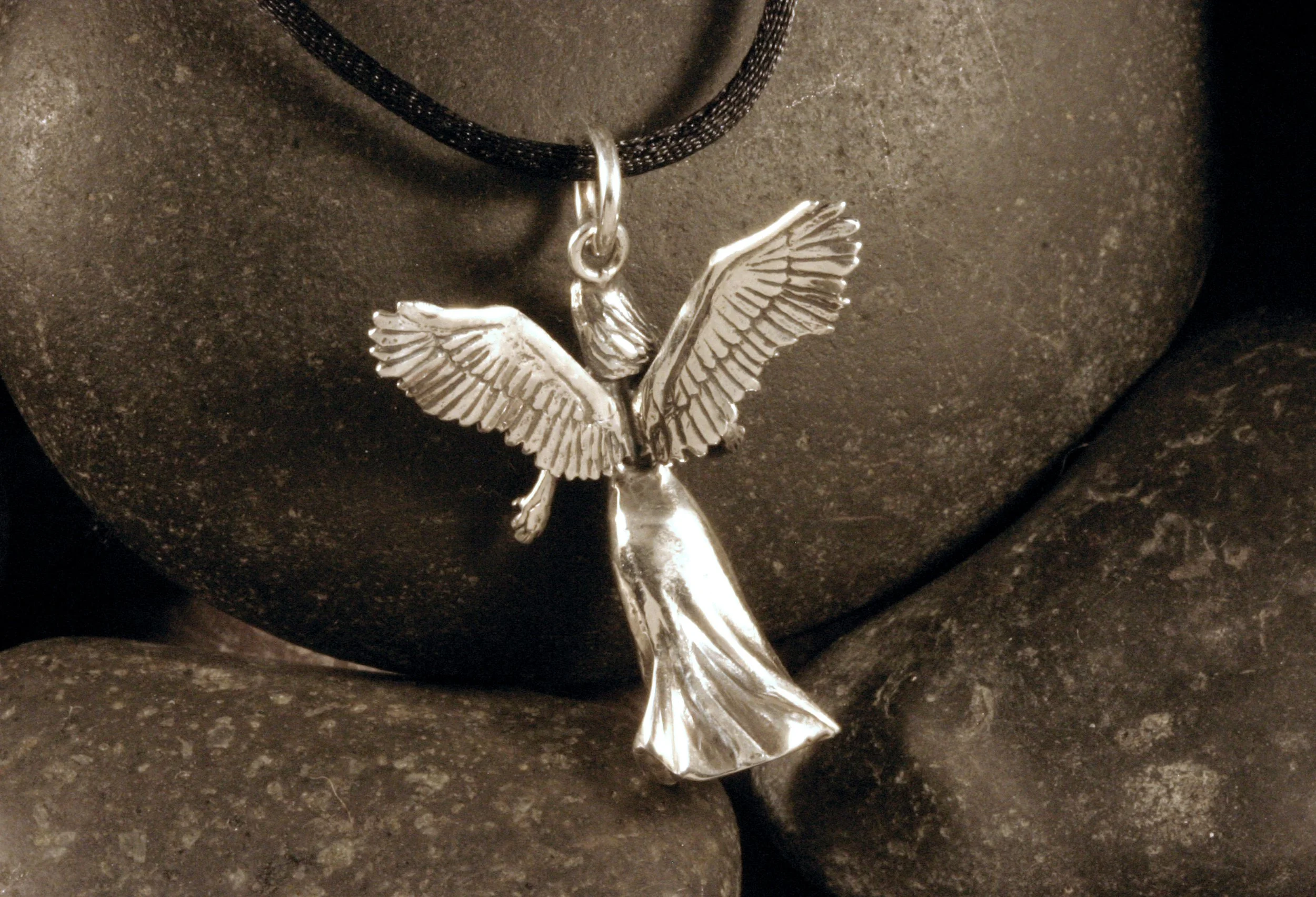 A back view of an oxidized sterling silver 3D angel pendant.