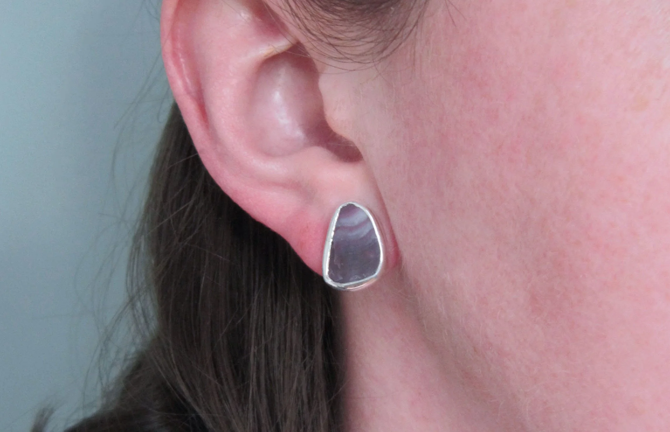 A model wearing sterling silver small sterling silver triangle wampum studs.