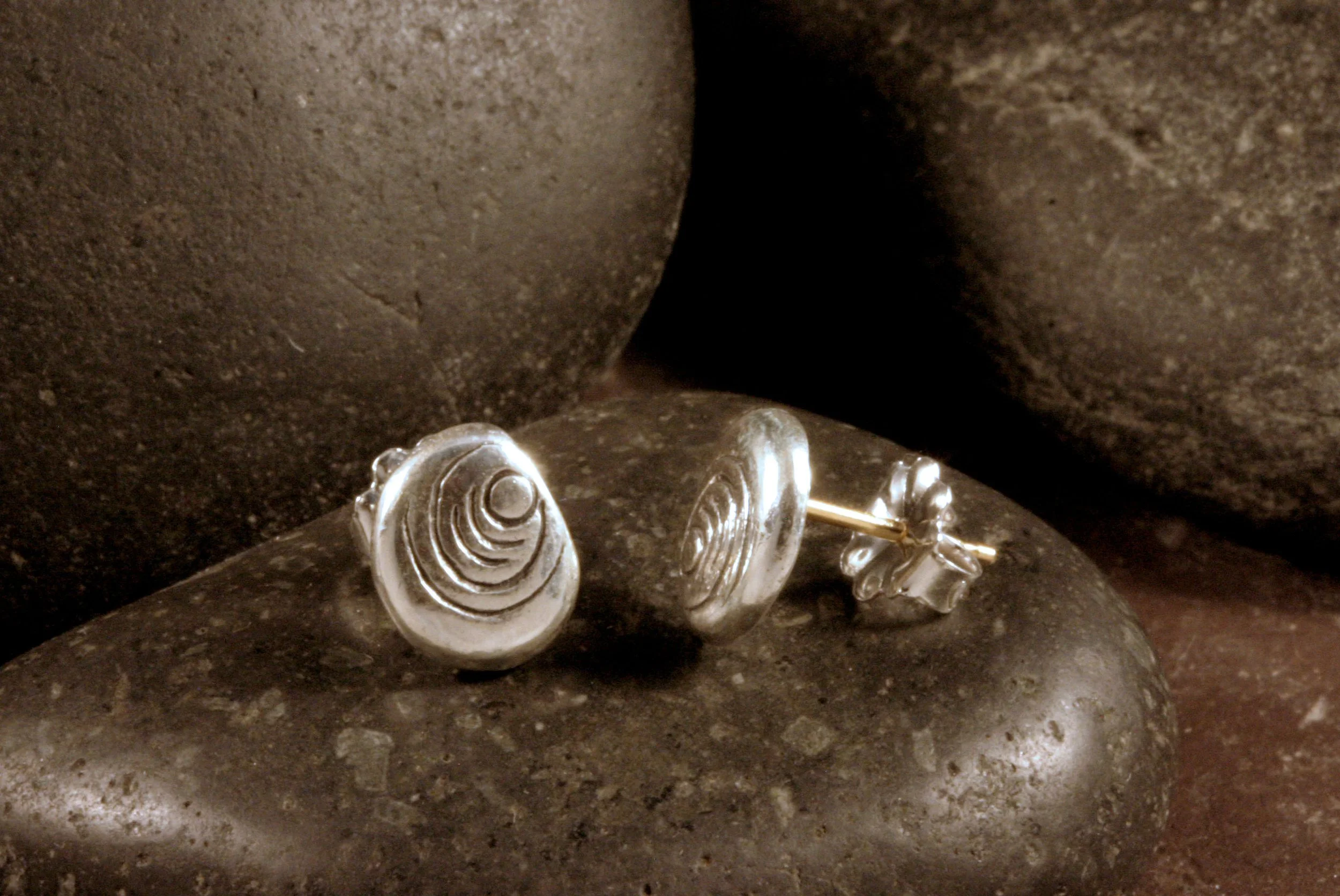 A side view of sterling silver dot ripple patterned stud earrings with 14K gold hypoallergenic posts.