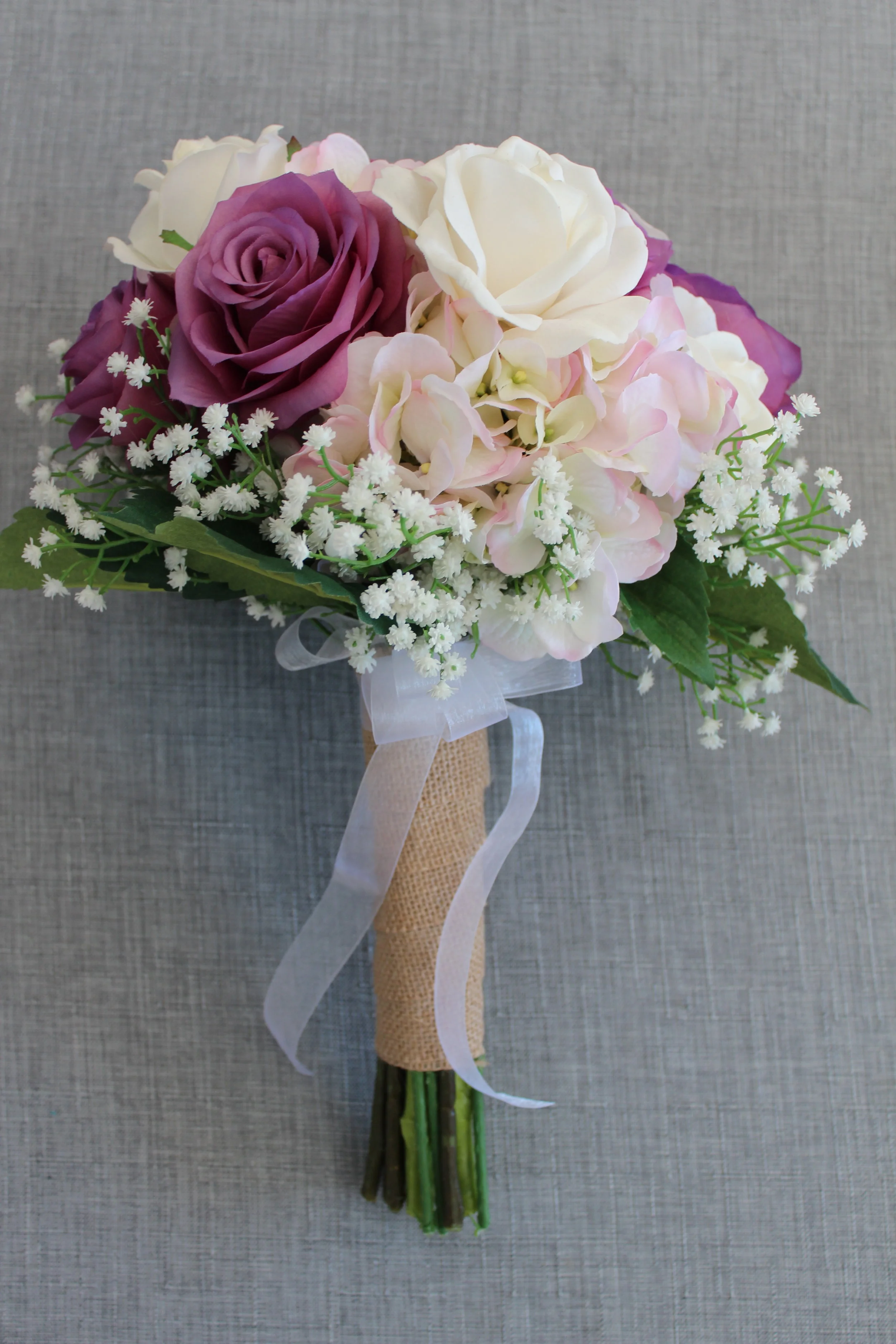 Cream Roses, Lavender Roses, Mauve Hydrangea, Baby's Breath, Hydrangea Leaves, Burlap and Ribbon.