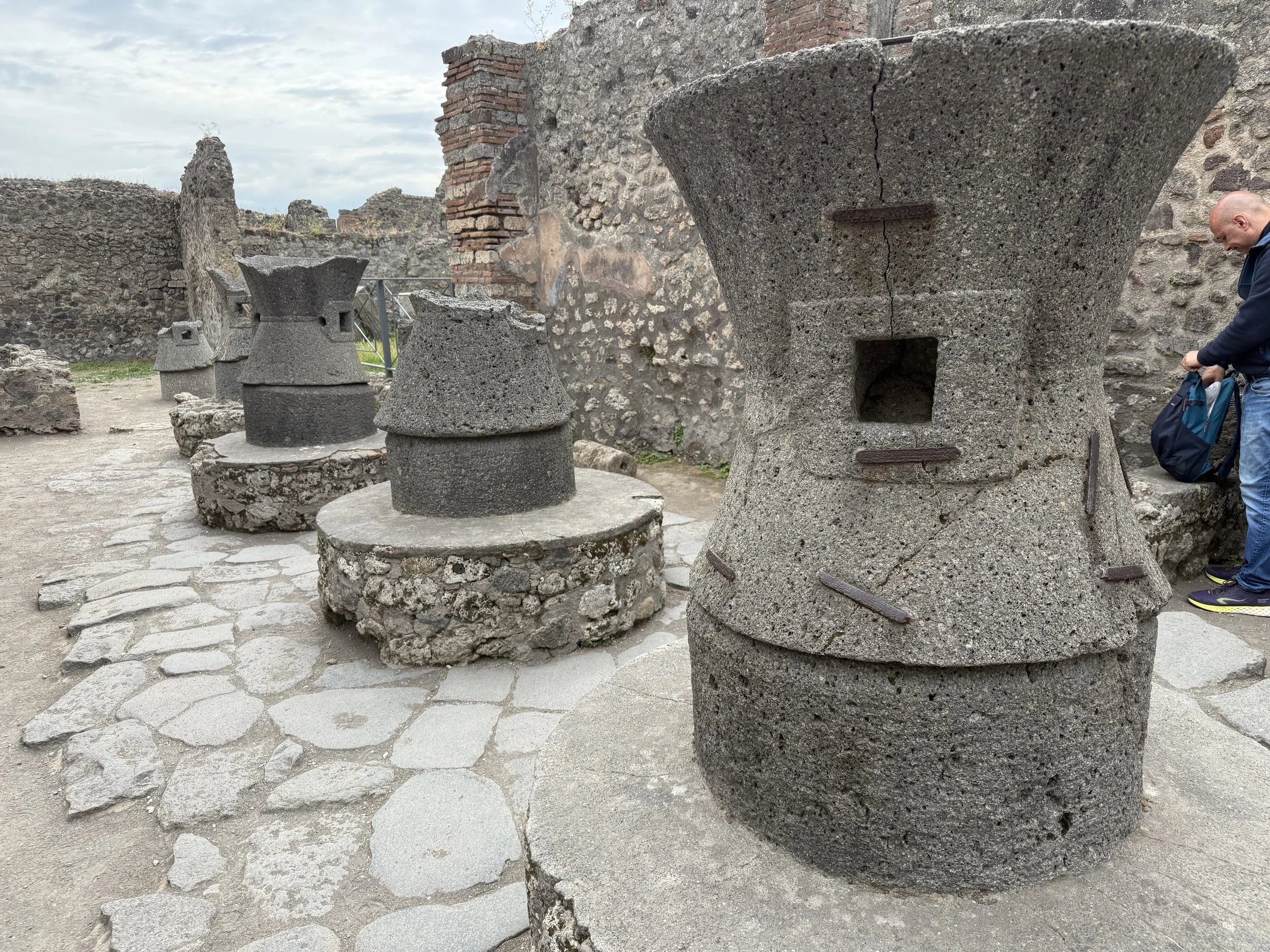 Ancient stone ruins with sculptures and walls, and a person with a backpack on the right side of the image.
