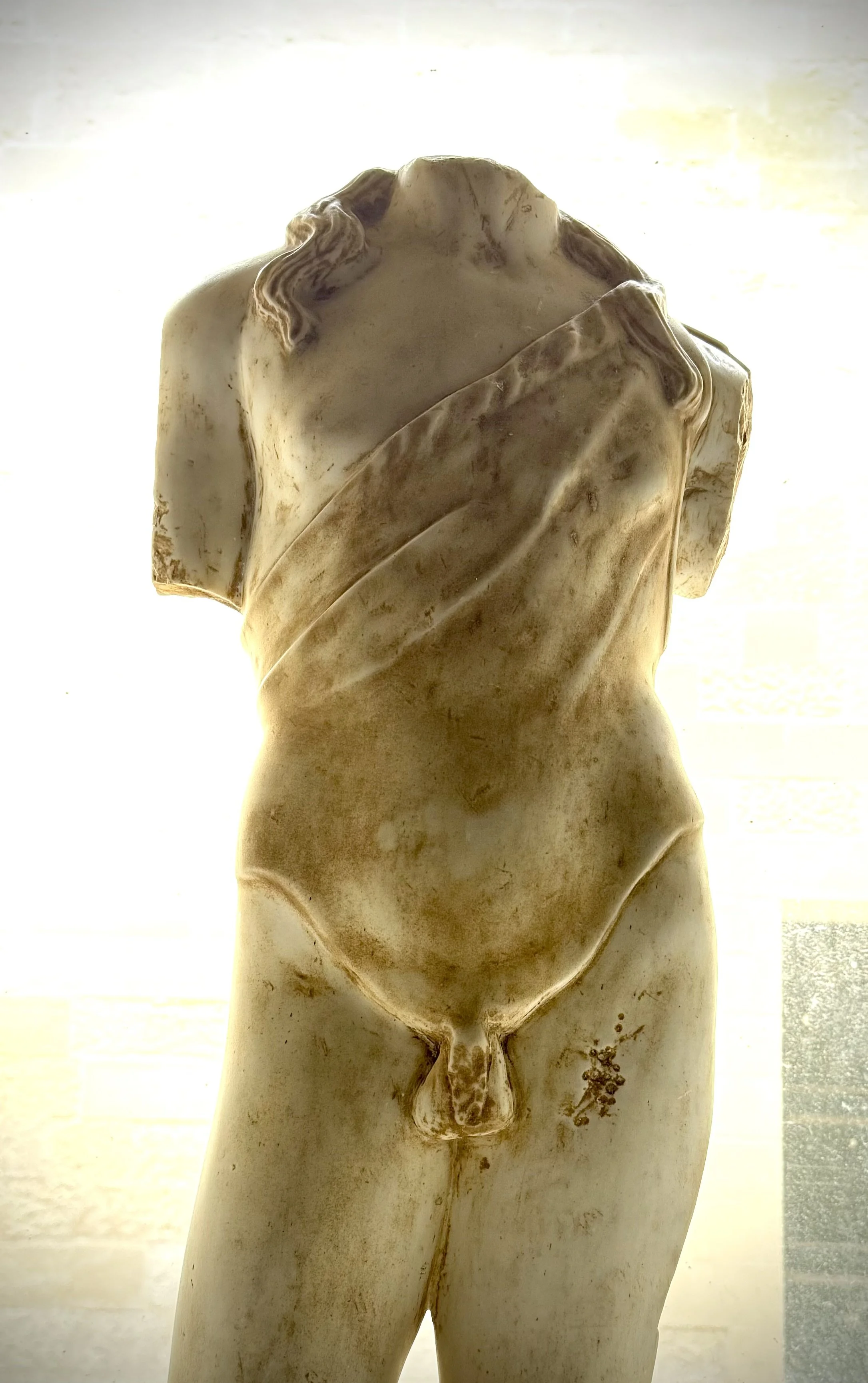 Close-up of a sculpture of a male torso, with detailed anatomical features and a cloth wrapped around the waist.