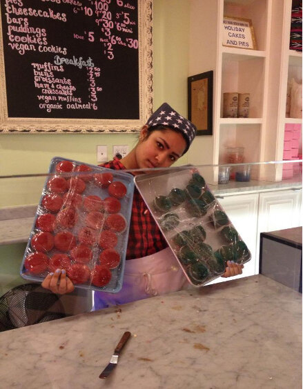 2013, Zenat holding up unfrosted cupcakes at a job that paid $7.50/hr.