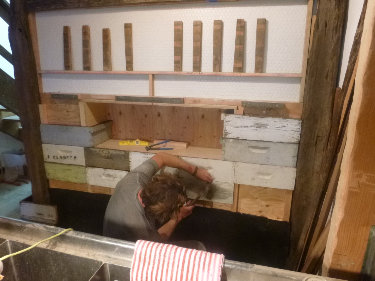  Hints of an Apiary: Nole installs bee hive box parts to the tap wall. 