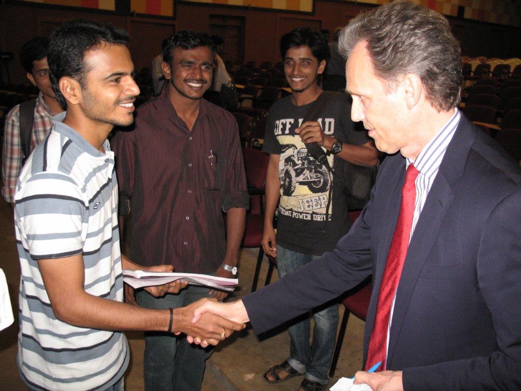 David Wiebers, M.D., shakes hands with student during Q&A session after the Theory of Reality presentation at Mangalore University.