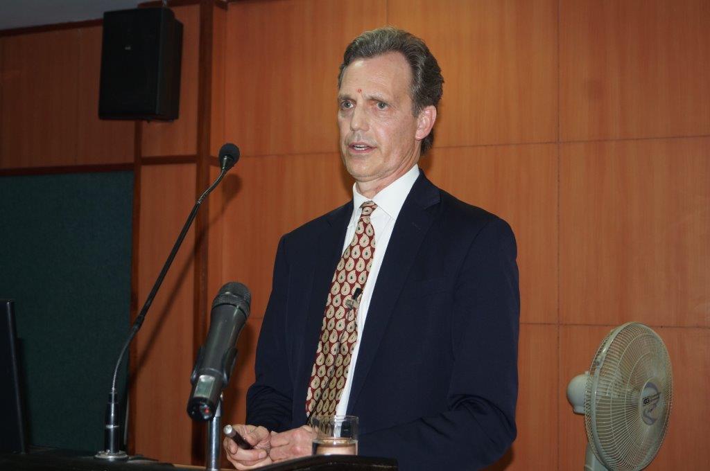 David Wiebers, M.D., at the podium at Amity University Delhi campus delivering Theory of Reality presentation on November 9, 2015. 