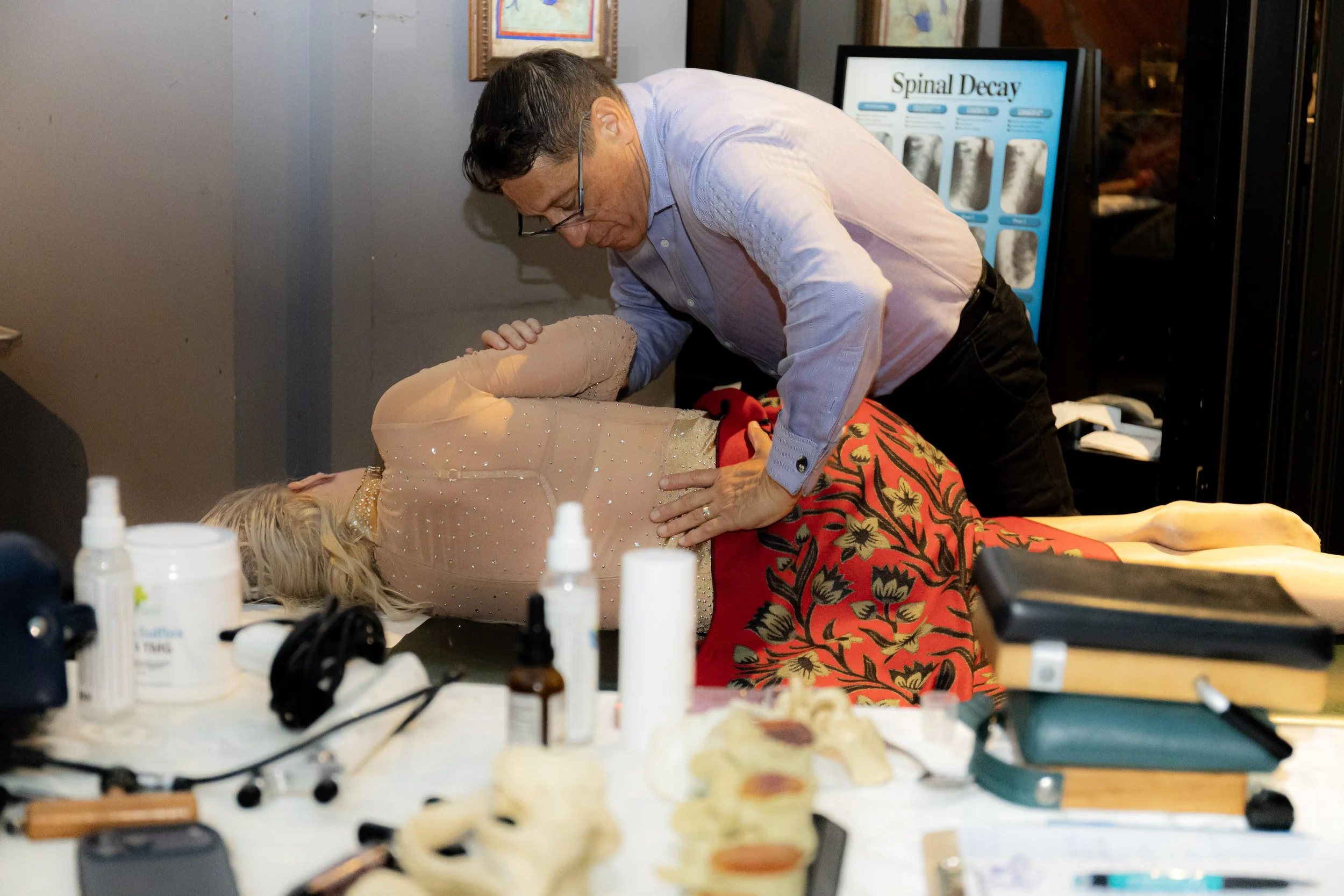 Chiropractor performing a spinal adjustment on a woman lying on a treatment table