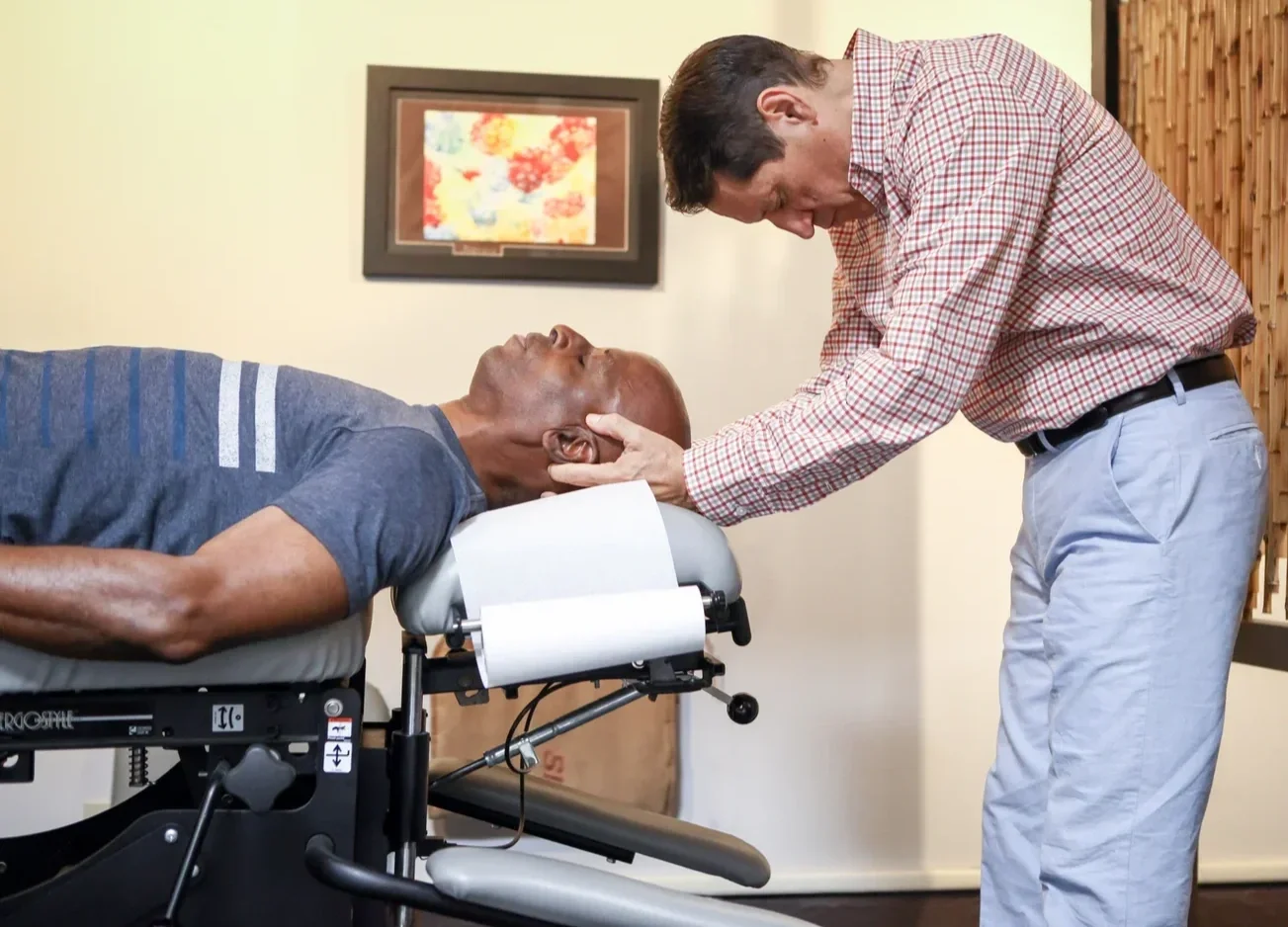 Chiropractor adjusting a man’s neck while he lies on a treatment table.