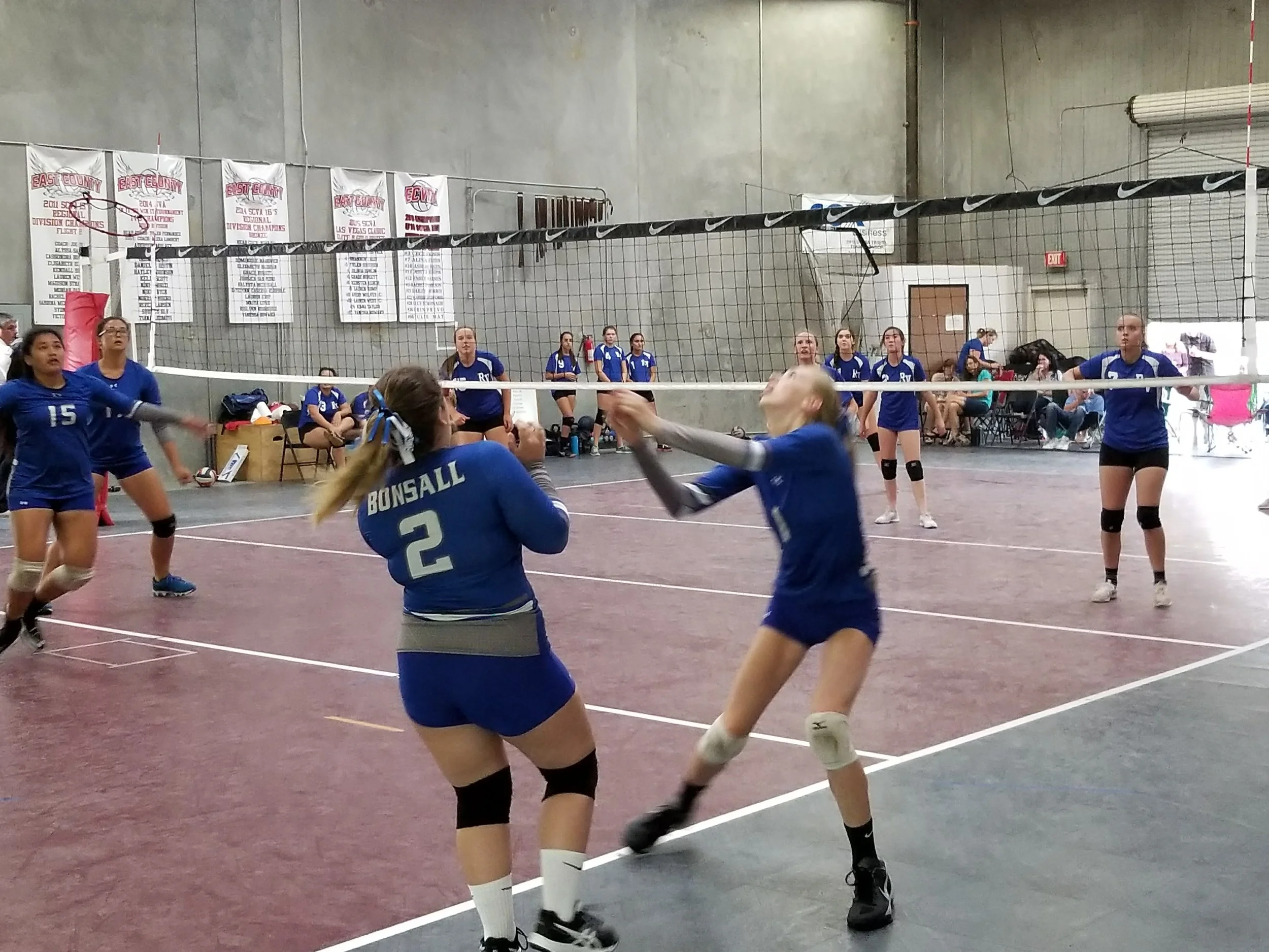 Abigail Reinard #1, stretches for a difficult setter-hit toward MaiCai Meluat #15 and Ashlin Smith (far left of court) in game 2, the first BHS win. Team Captain Alexandra Beker #2, calls the shots.