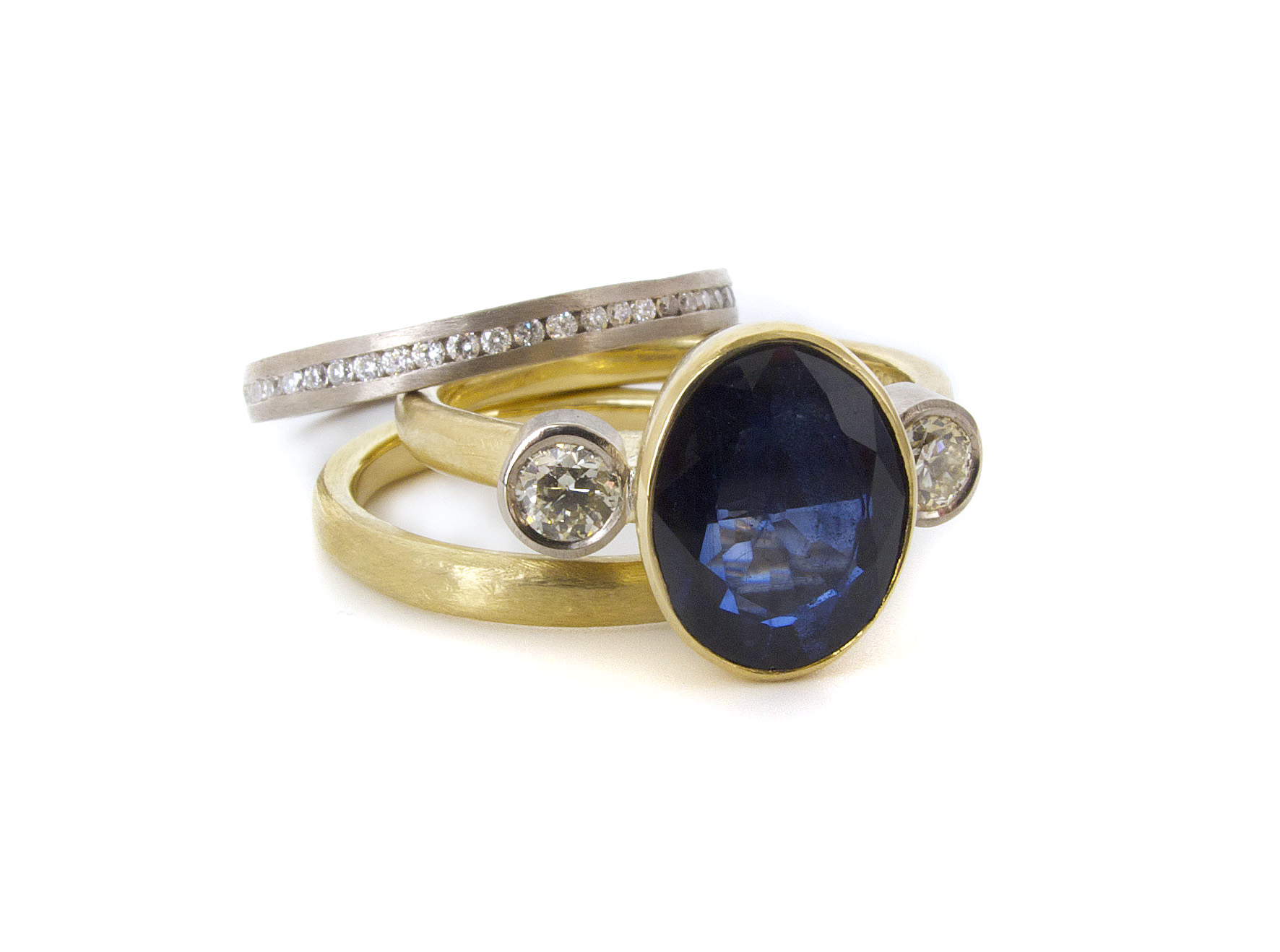 This remake of an engagement ring with the customer's own oval sapphire and diamonds into a beautiful new trilogy engagement ring completed with wedding band and diamond eternity band. All 18ct white & yellow gold, with a soft organic textured look to the bands.