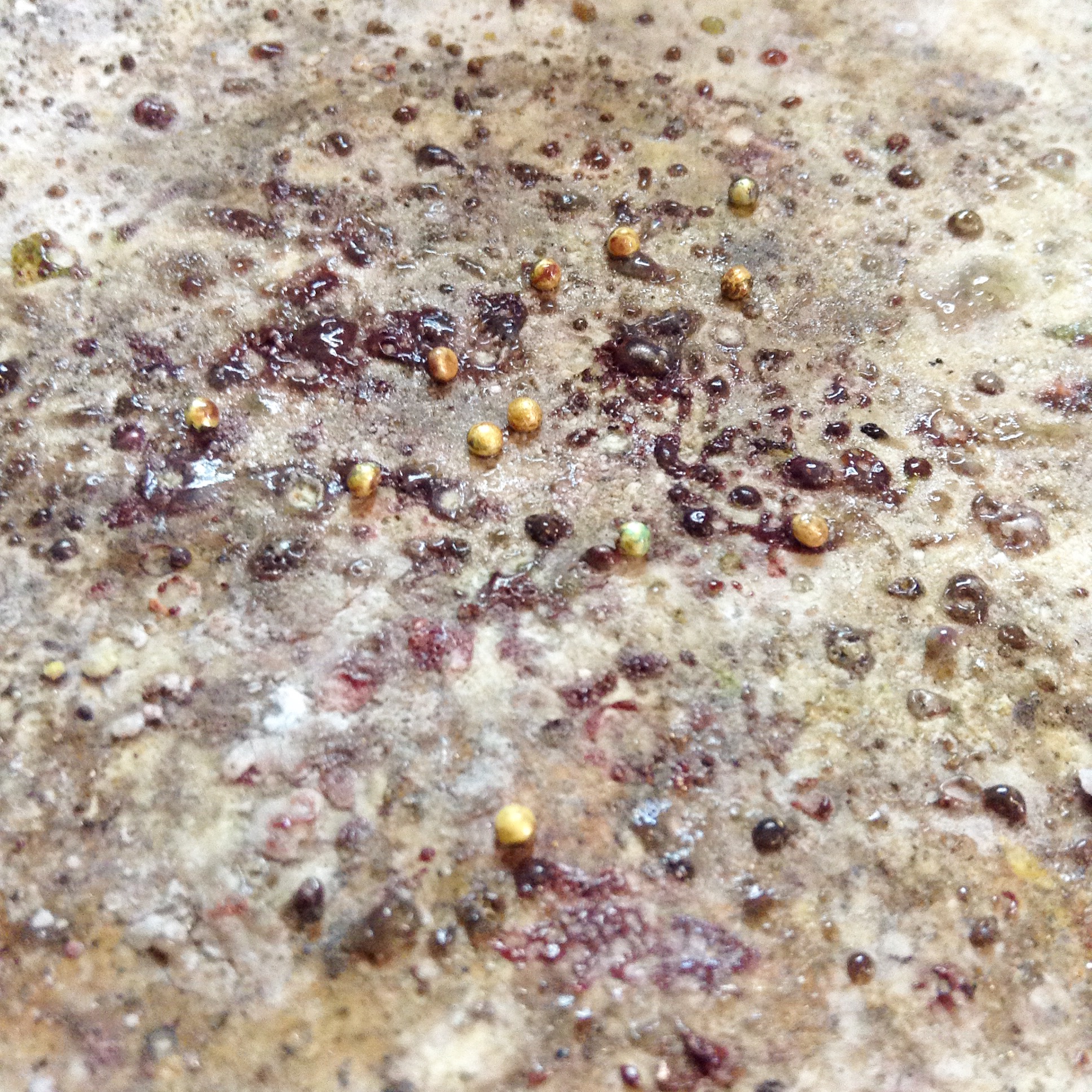 Balled up bits of gold, granules, sit amongst the flux on the solder mat