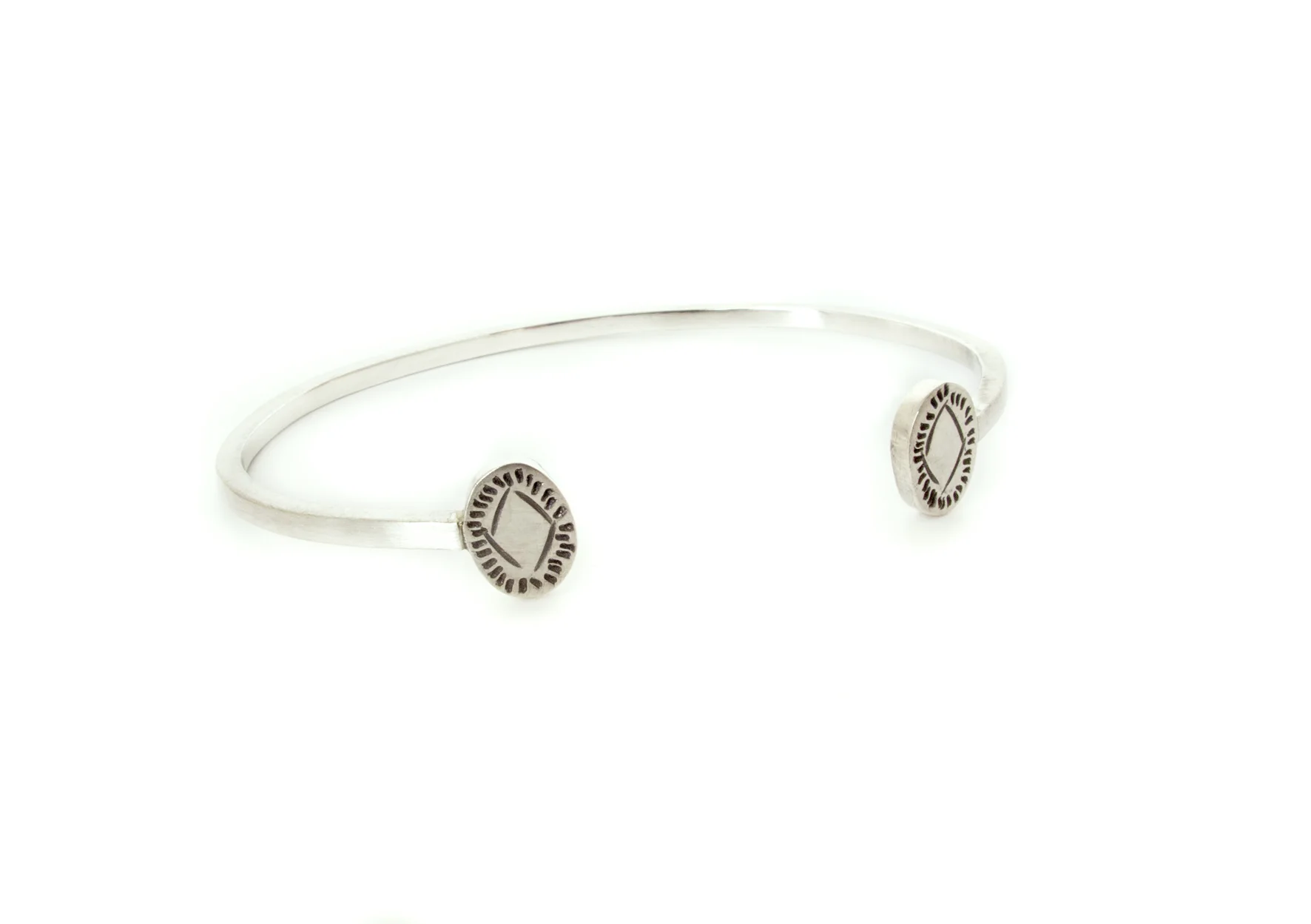 this wrist cuff has some subtle detail on each end, oval shaped with fine hand stamped details, in sterling silver.