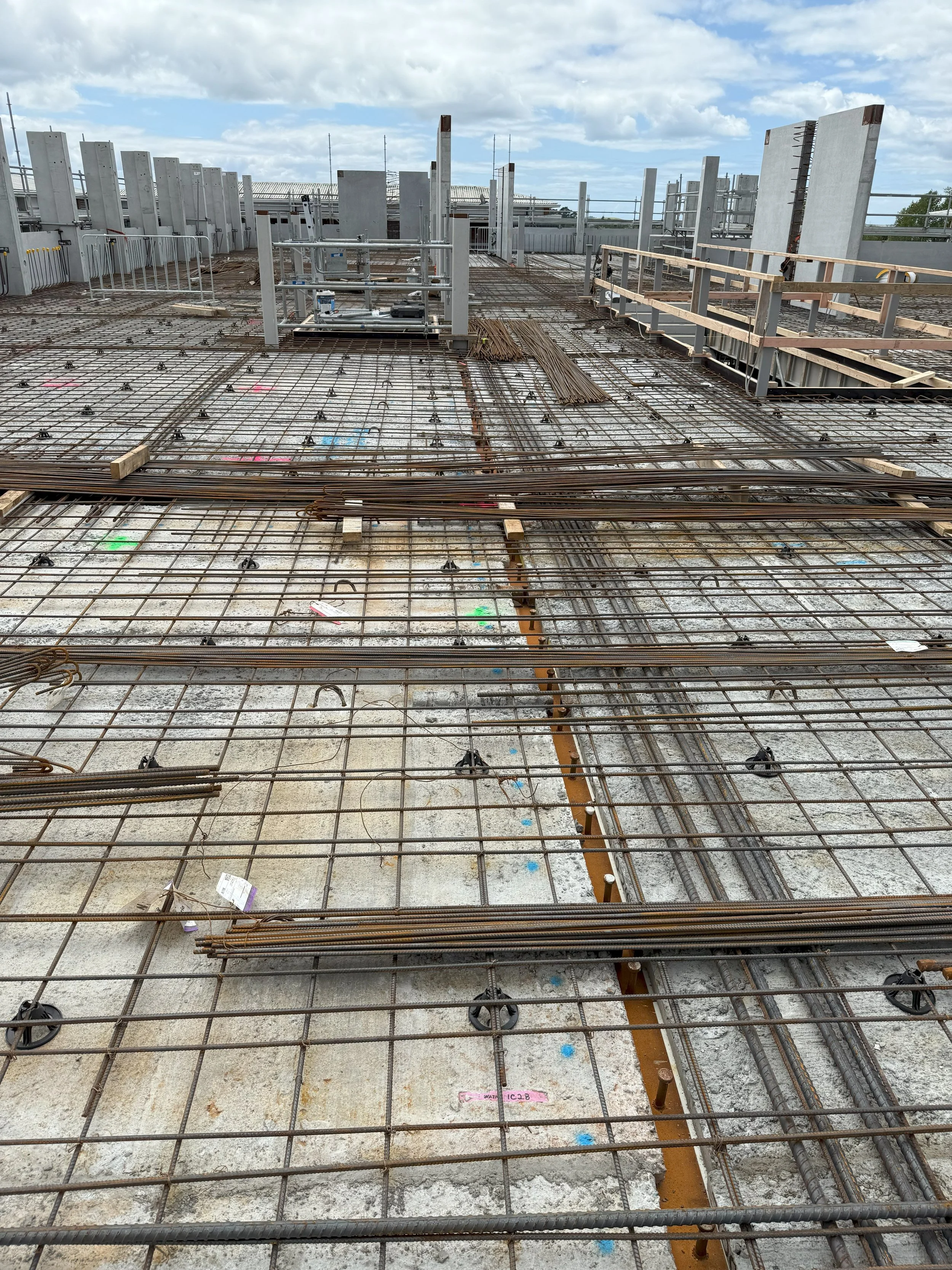 Construction site with exposed steel rebar and concrete, awaiting pouring of a new floor or slab.