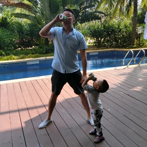 Alex in the backyard drinking a soda with his son.