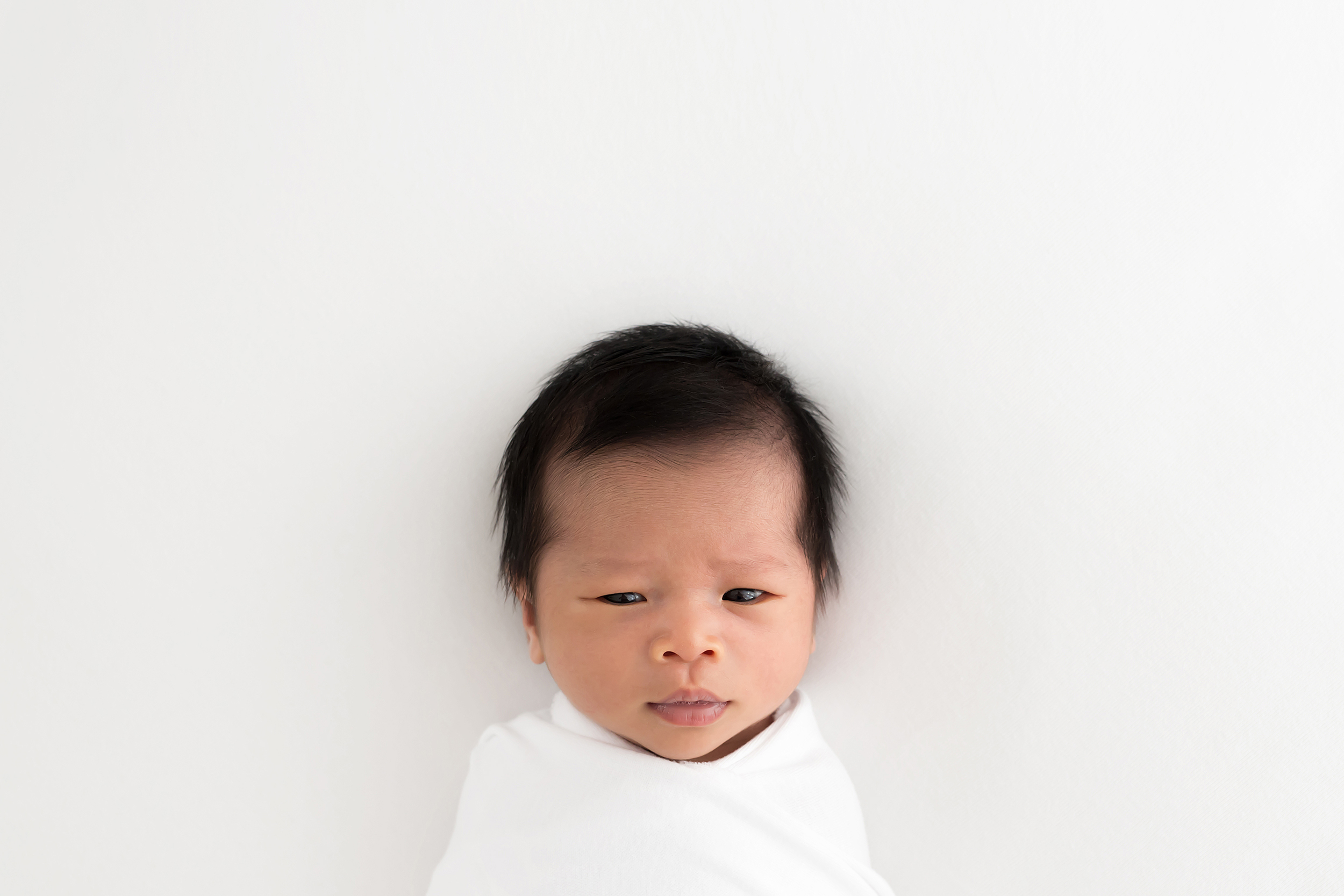 Professional photo of a newborn baby with her eyes open and looking at the camera taken during a baby photo session in Melbourne