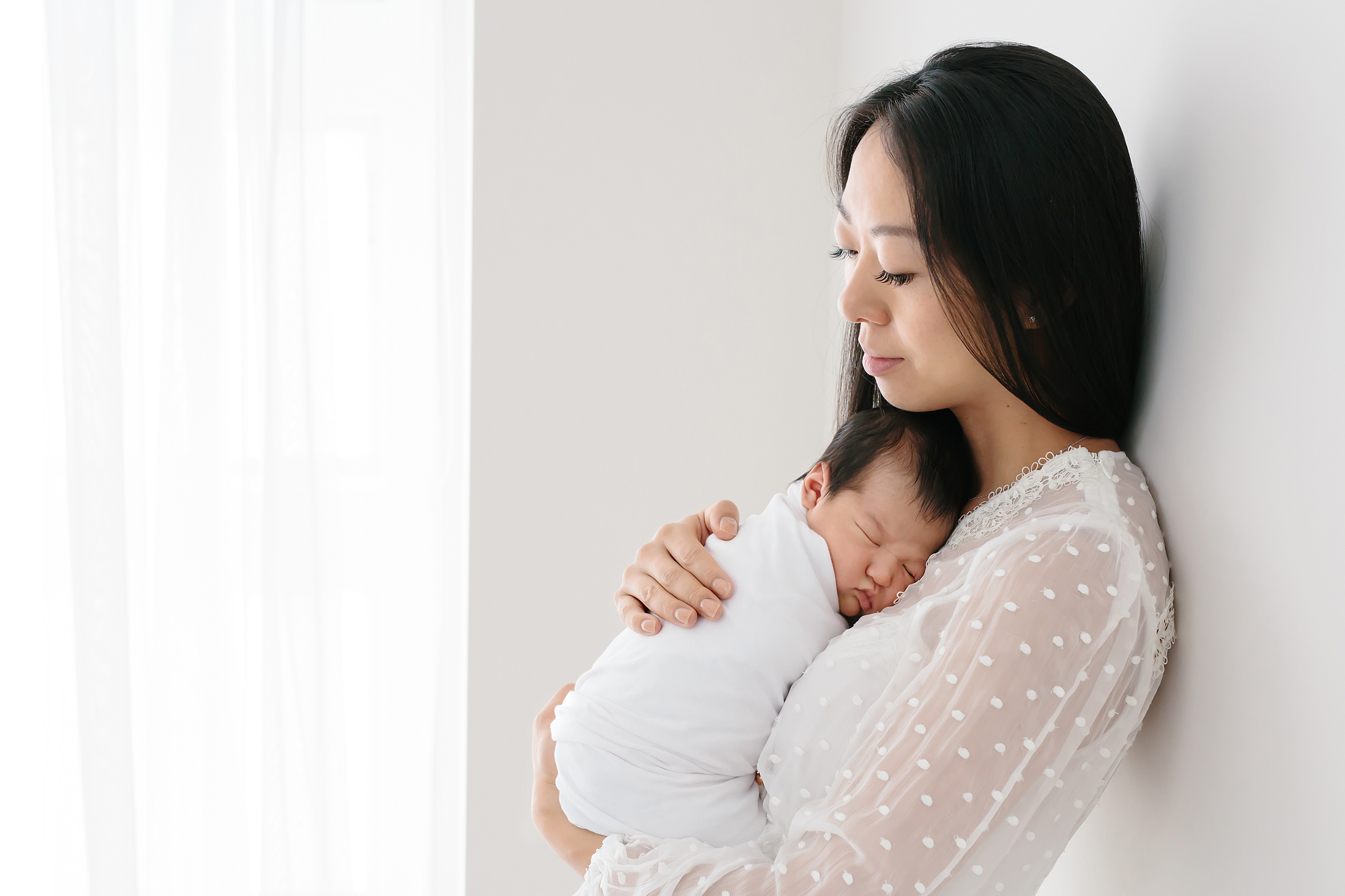 A mother holding her newborn baby on her chest taken during a newborn photography session in Melbourne.