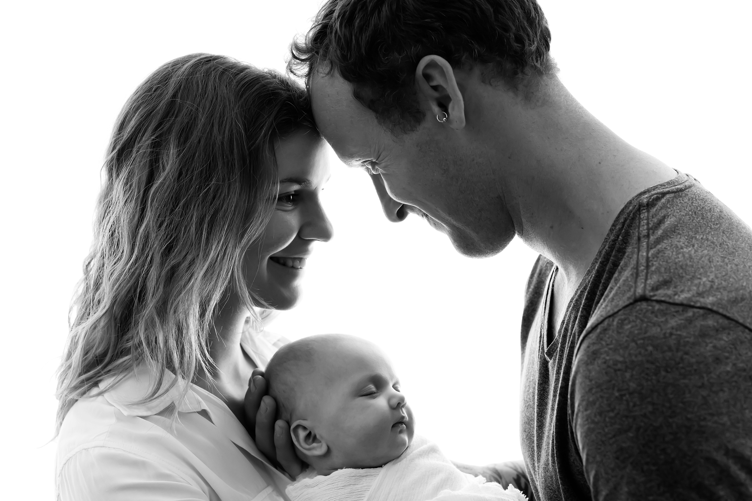 Photo of a Melbourne couple holding their newborn baby girl during a professional photo session.