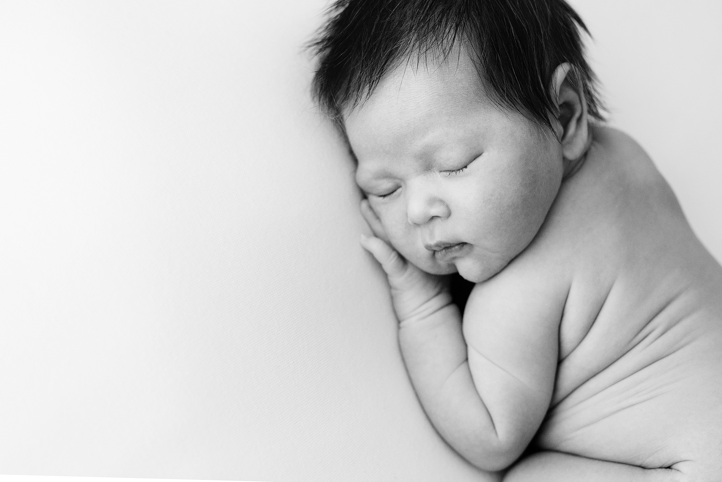 A newborn baby girl sleeping on her tummy in black and white taken by a Melbourne newborn photographer