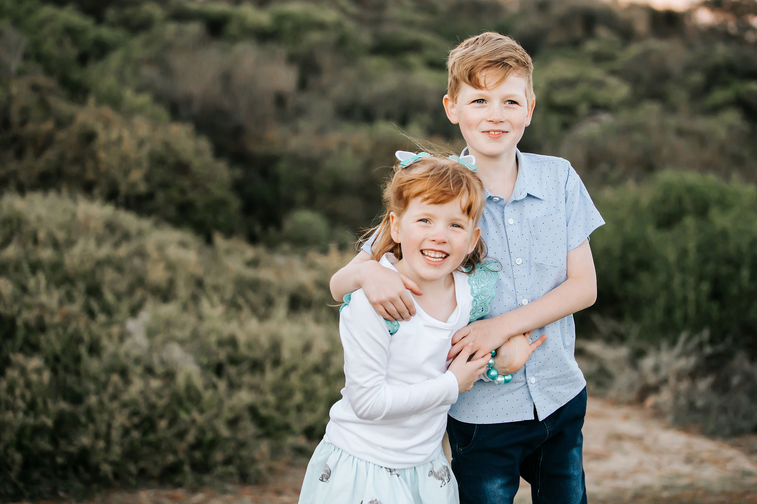 A natural photo of a brother and sister having a cuddle taken in Melbourne during a family photo shoot