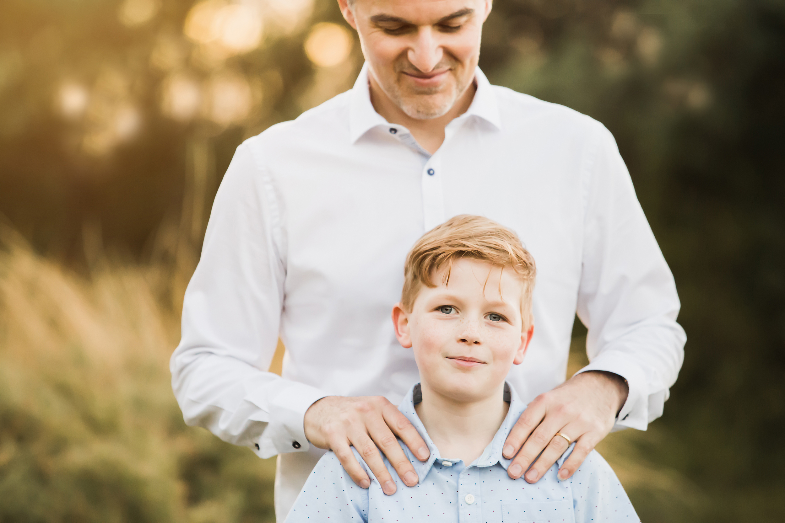A photo of a father and son, dad has his hands on the son's shoulders.  This was taken at a family photography session in Melbourne