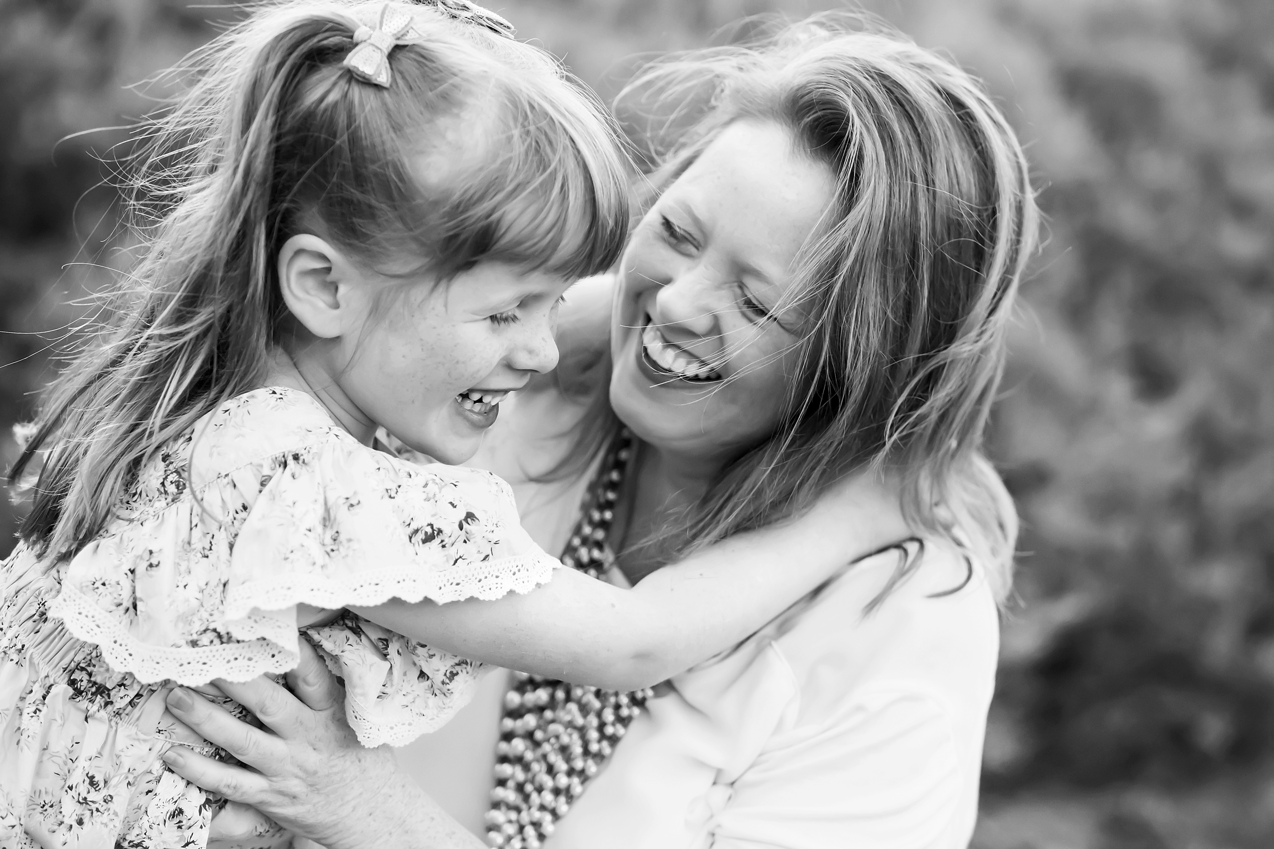 A black and white photo of a mother and daughter laughing together taken by a family photographer in Melbourne