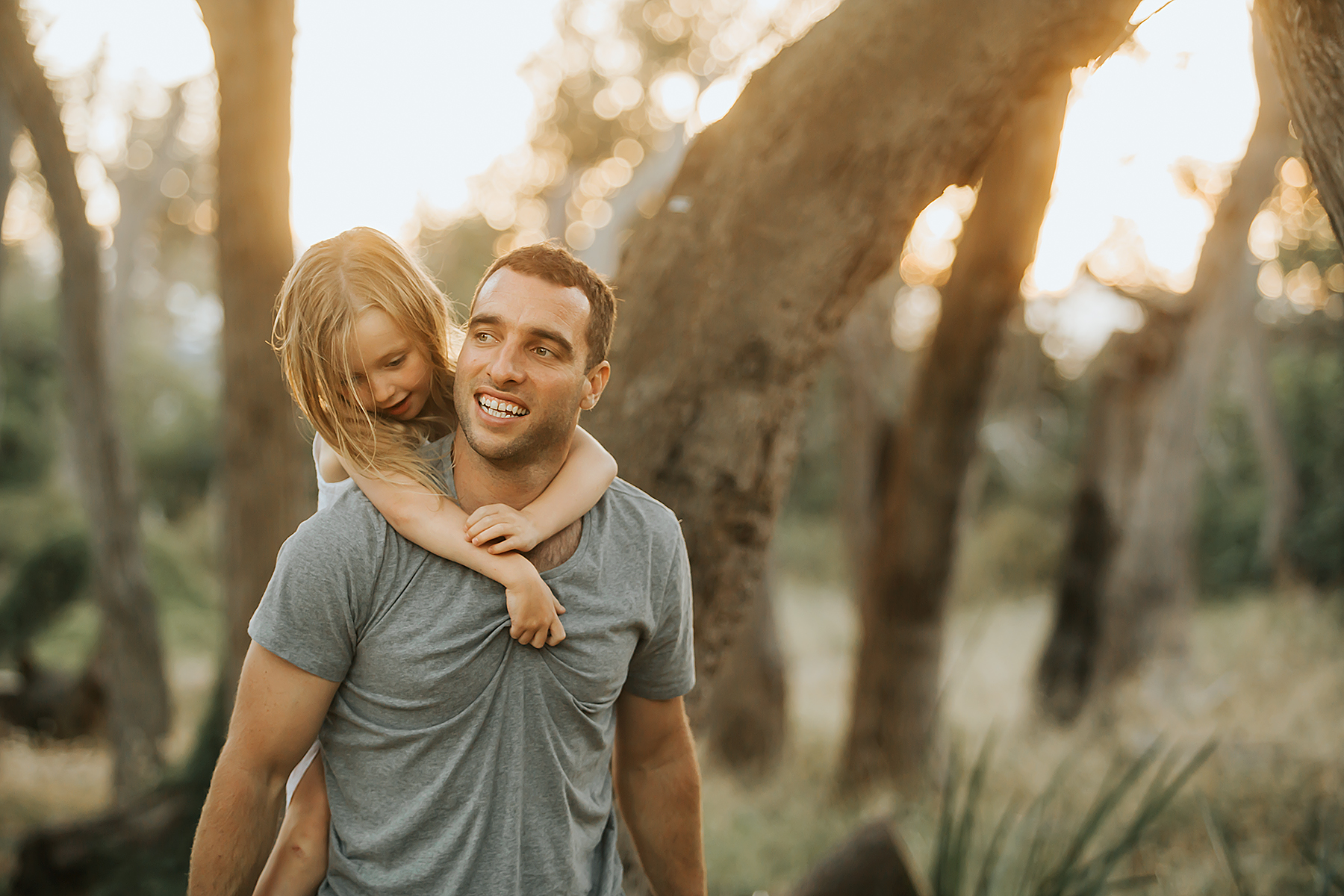 Taken during golden hour on the Mornington peninsula, a girl having a piggy back on dad's back during family photo session.