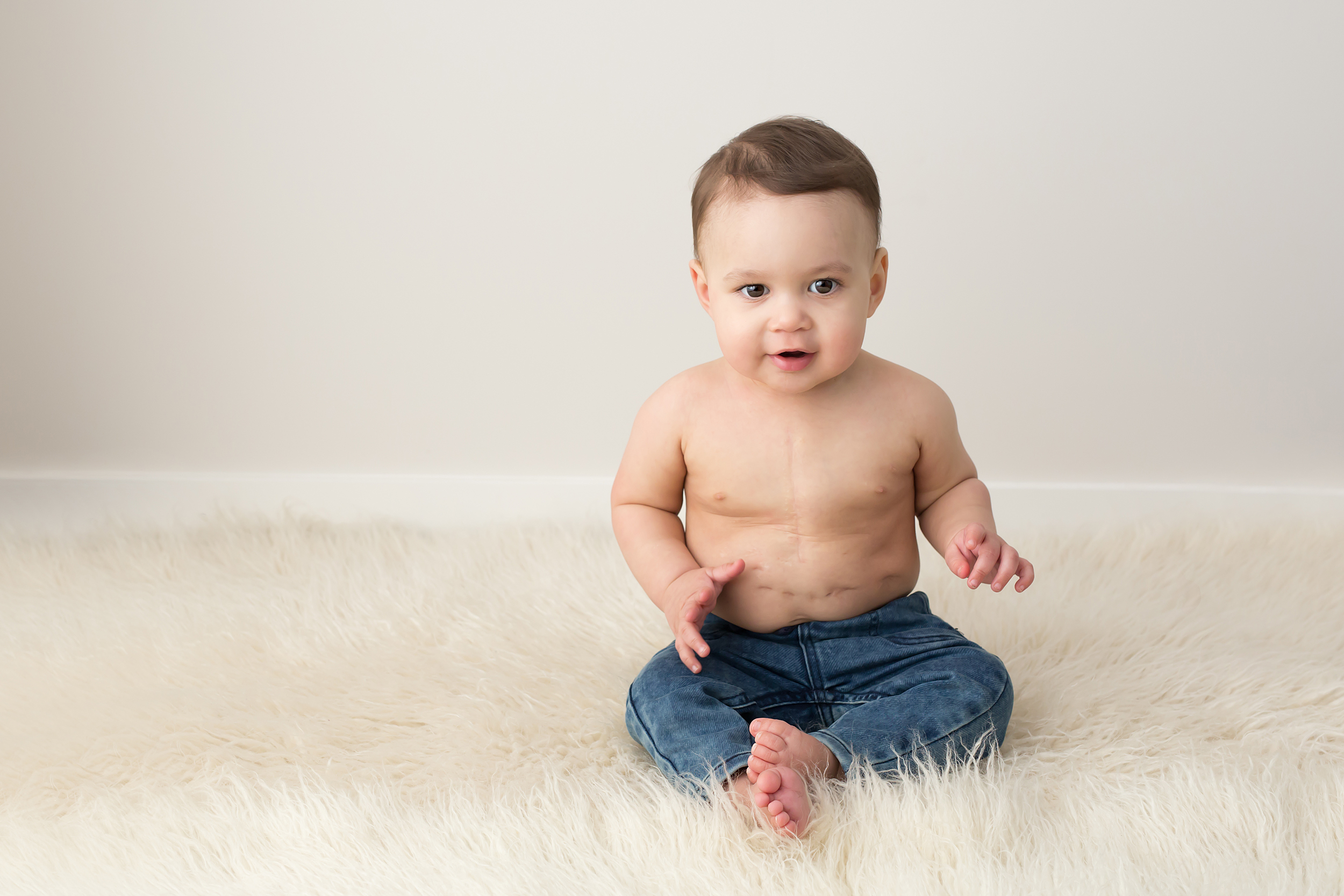 Toddler sitting on fluffy rug at baby milestone session in Melbourne