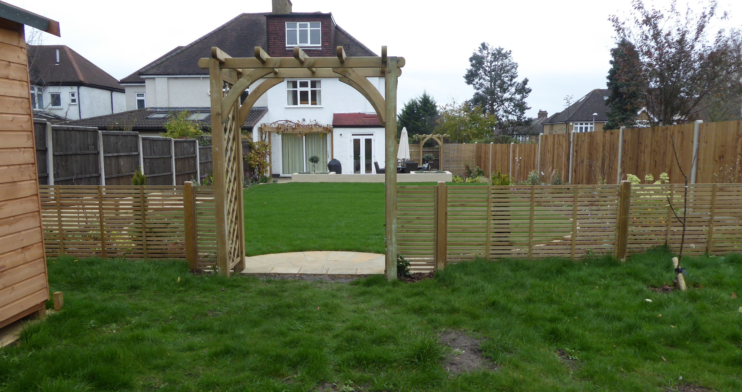 Looking back down the garden through the arch and trellis that separates the main garden from the meadow area that contains a large shed, and in future, a garden office.