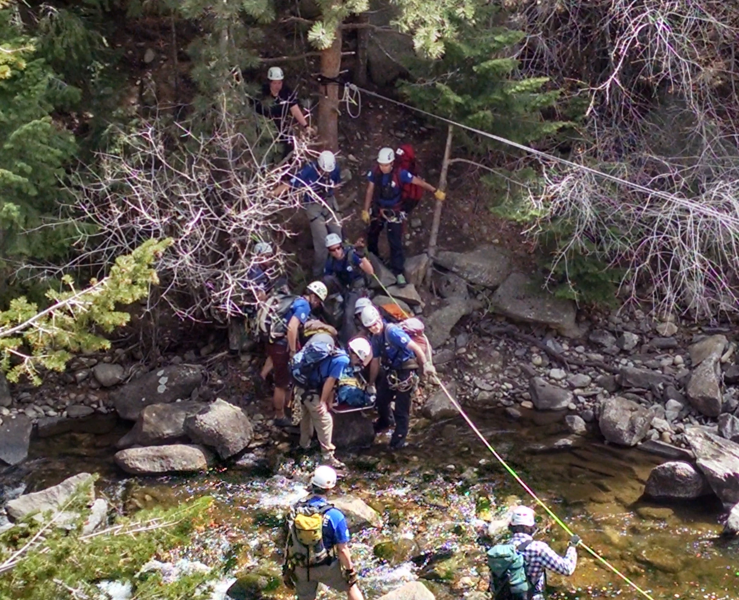 Rescuers carrying the litter borne patient across Boulder Creek at a low-water crossing.