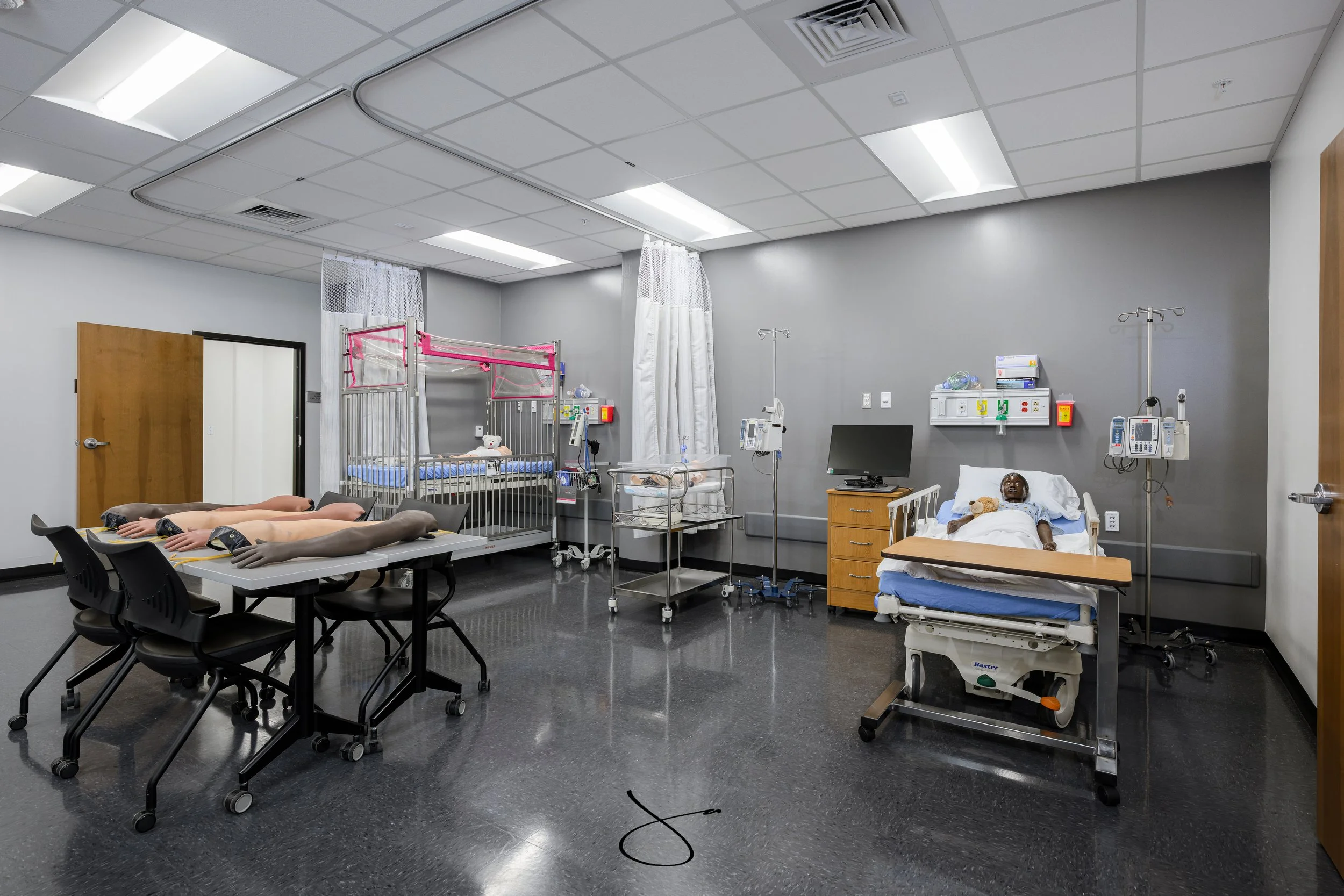 Hospital room with medical equipment, patient beds, and mannequins used for training.