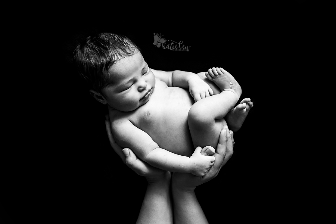 baby in mom's hands on black background