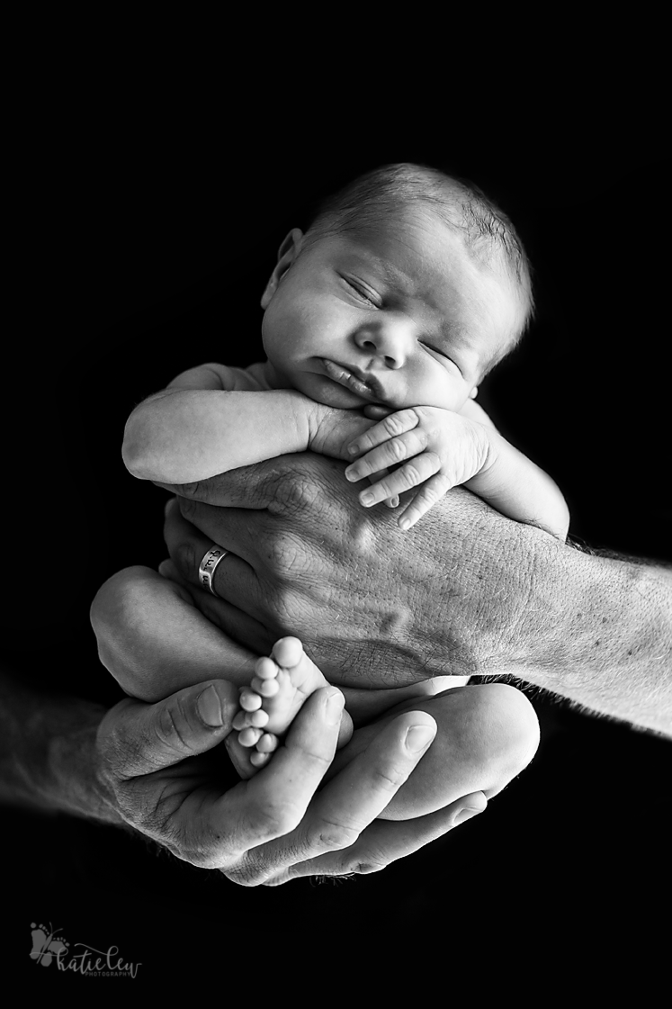 baby in dad's arms on black background