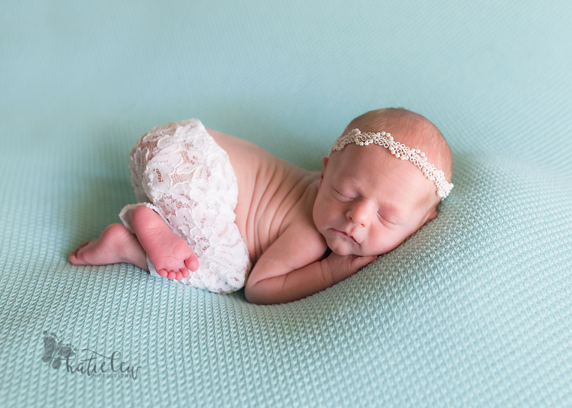 baby girl wearing lace pants on a blue blanket