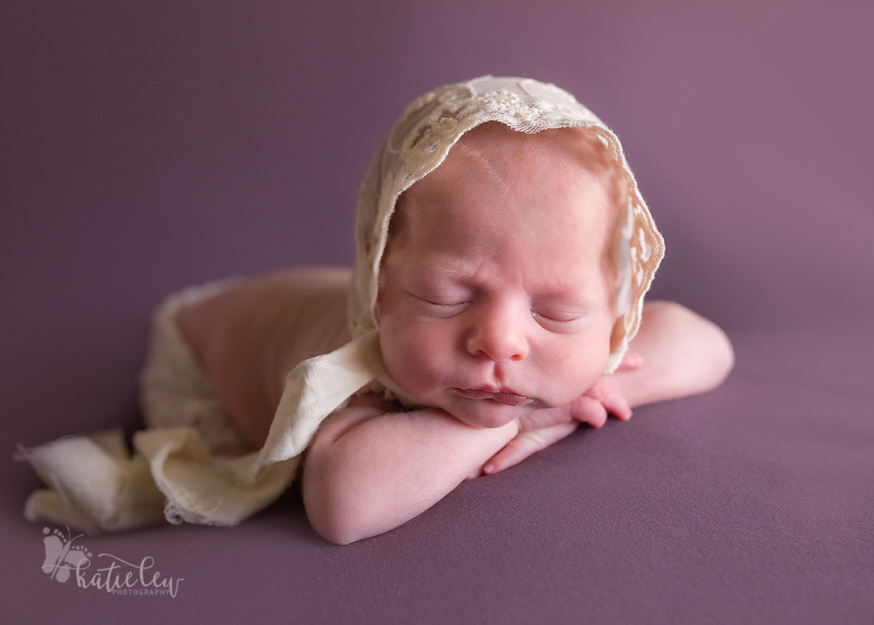 A baby girl twin wearing a lace bonnet