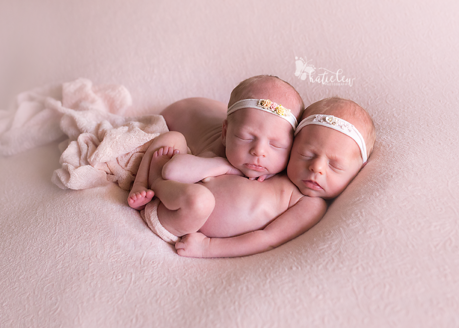 Two baby twin girls snuggled up with each other