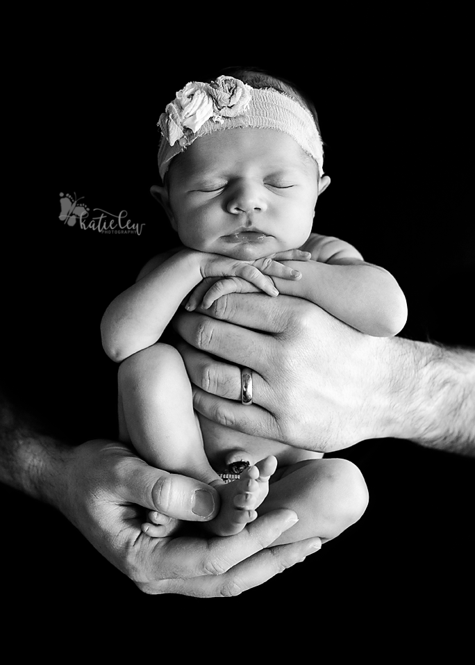 A newborn girl wrapped gently and safely in her daddy's hands