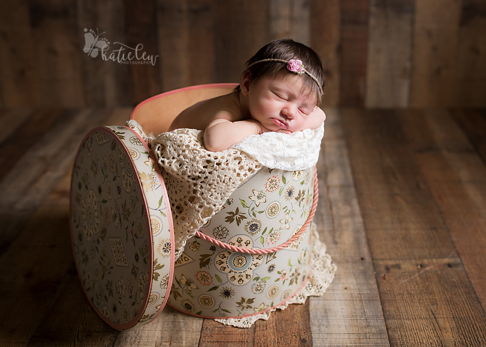 Newborn girl resting peacefully in an antique hat box