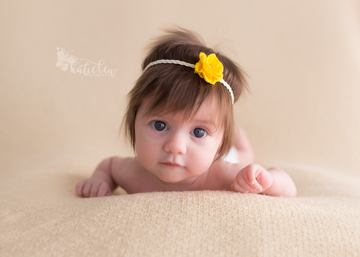 baby girl with a head full of hair wearing a yellow flower