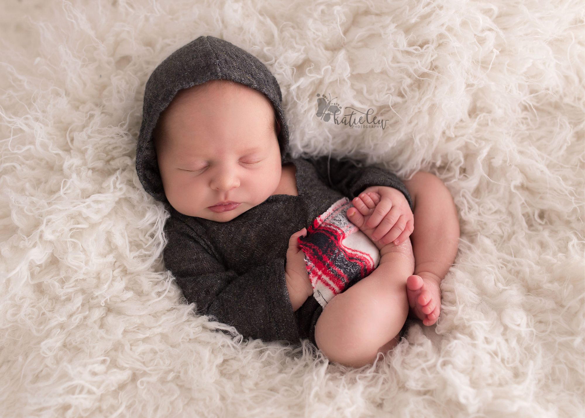 Newborn wearing a hooded romper with her hand in her pocket