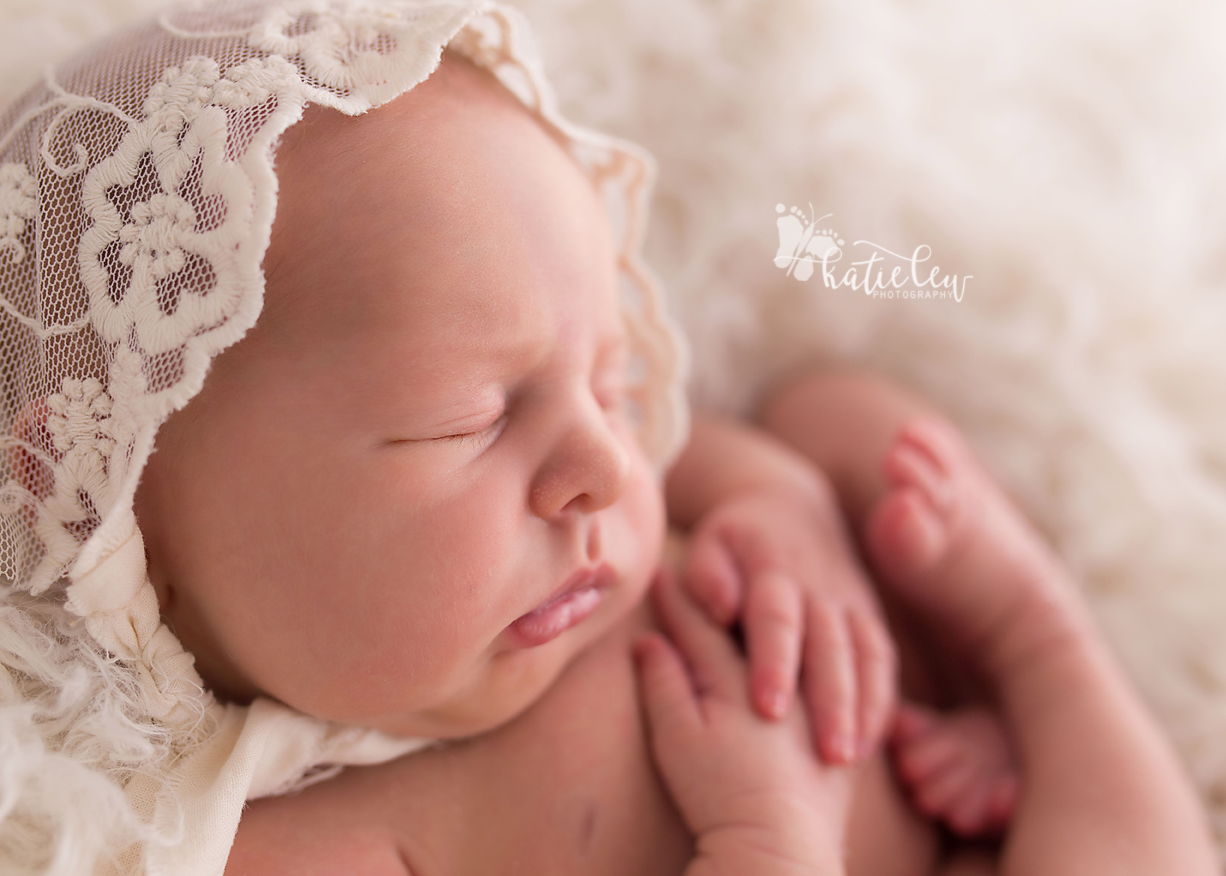 newborn girl wearing a lace bonnet and nestled in fur.