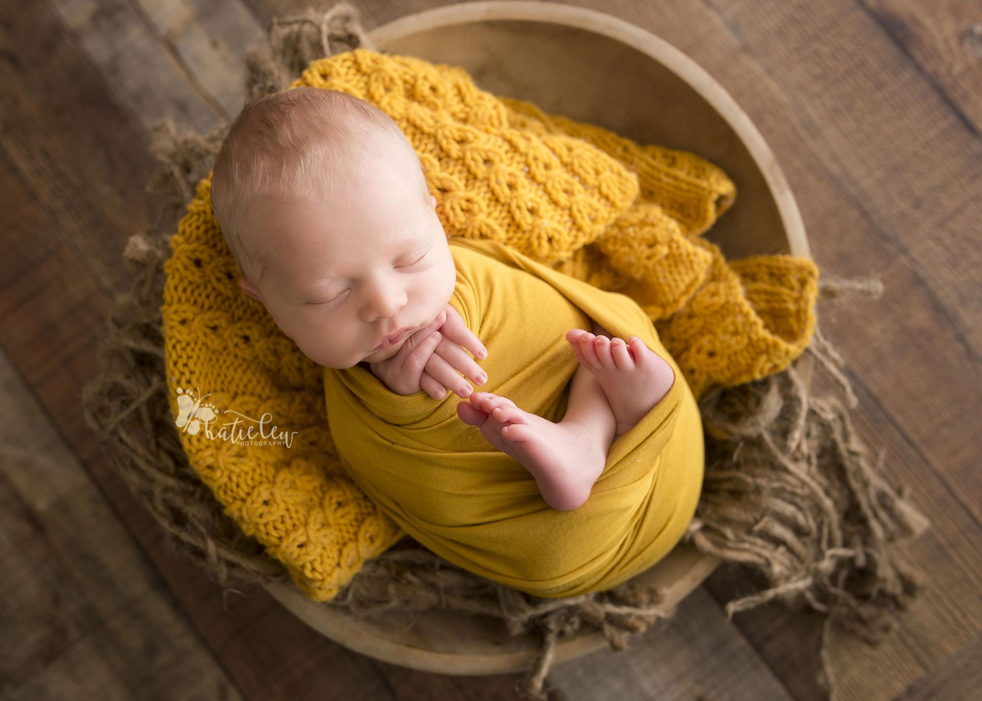 newborn boy wrapped in mustard and nestled in a bowl