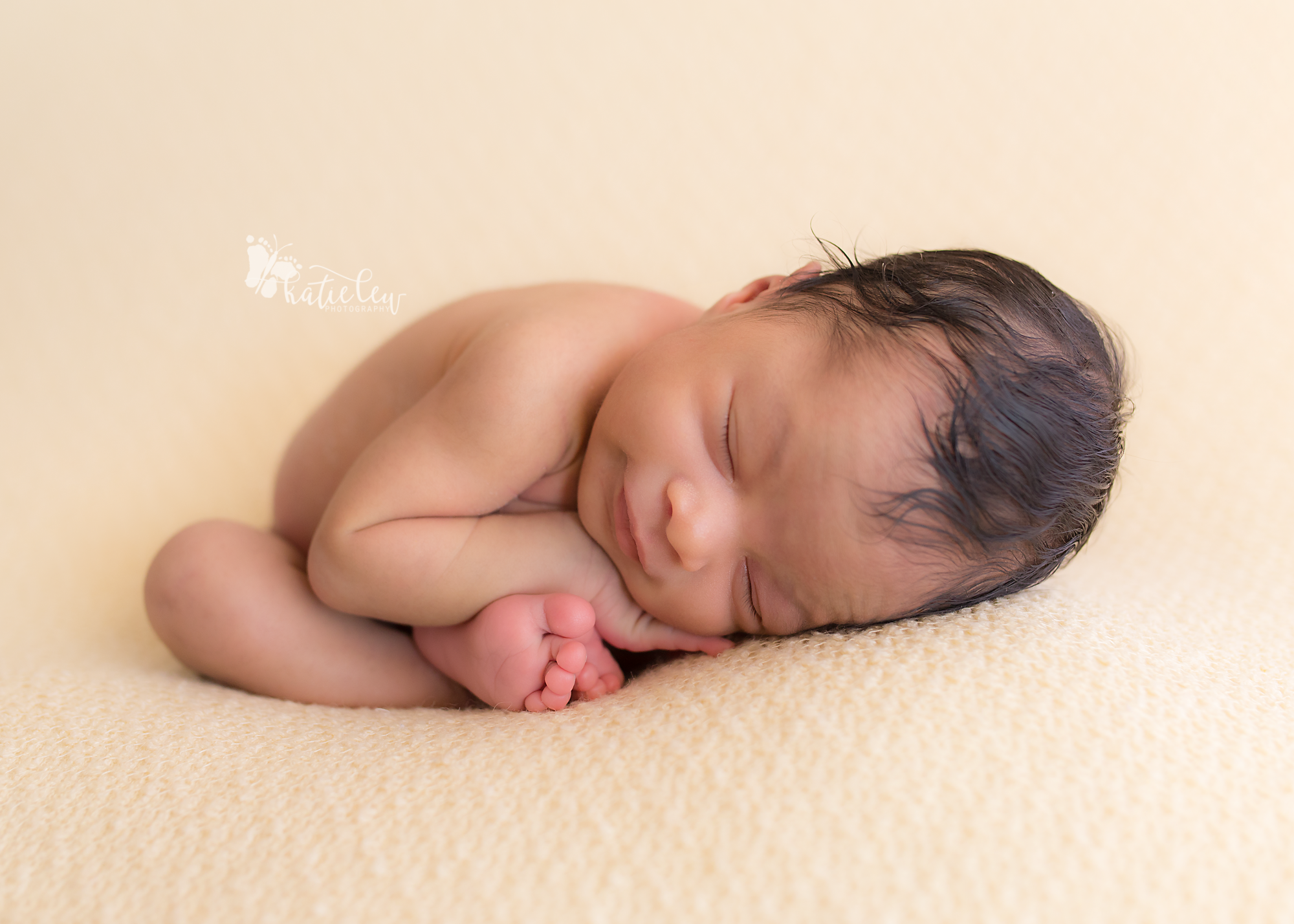 womb pose with a newborn girl on a cream backdrop