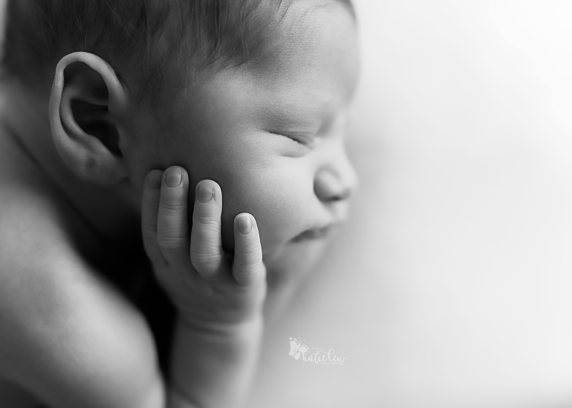 A sweet newborn boy holding his cheeks